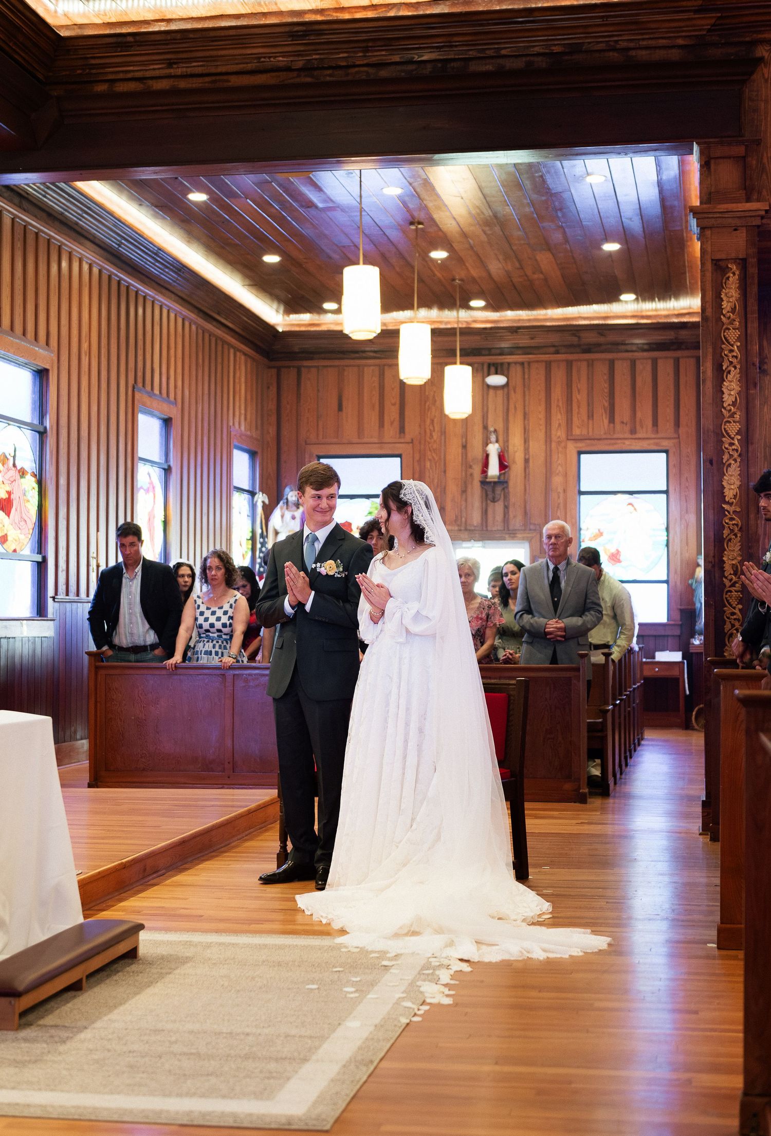 Bride and groom walk down the aisle of a wooden church during their wedding ceremony.