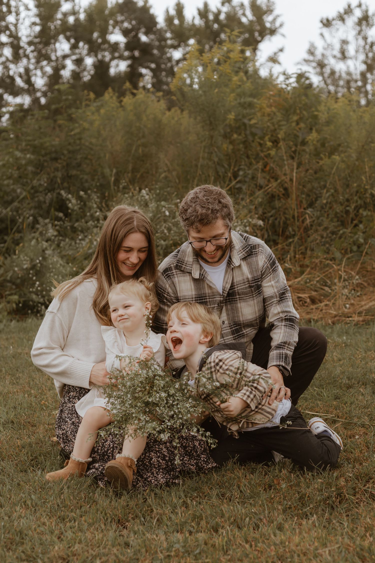 Family lying in grass together sharing joyful moments with wildflowers.