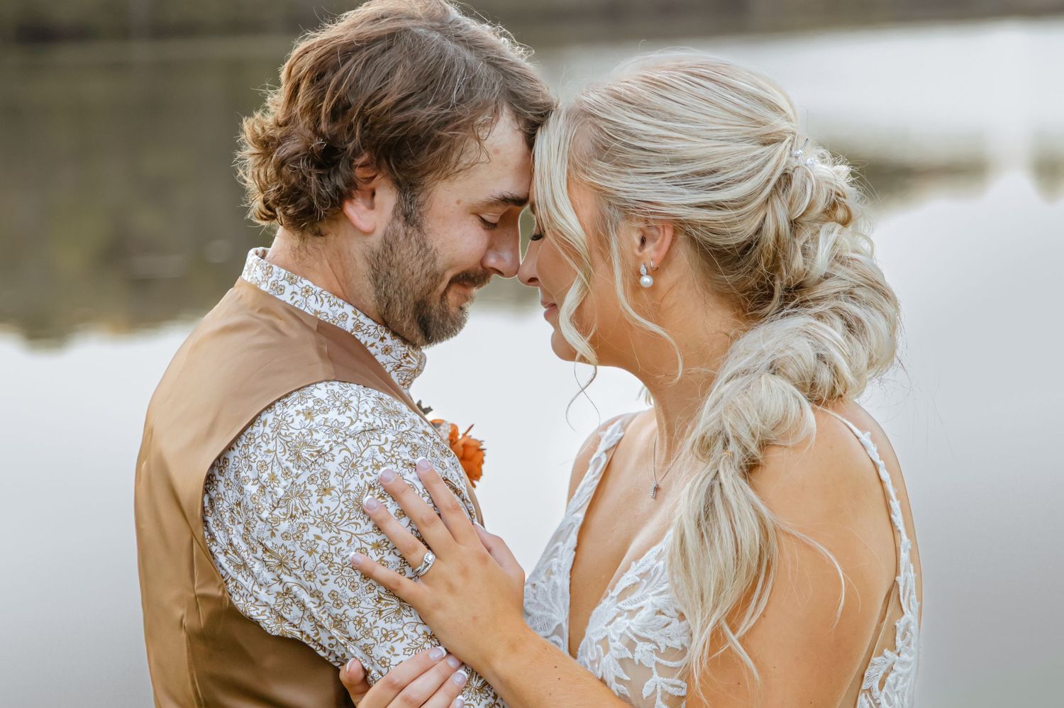 Intimate wedding portrait by a serene lake during golden hour.