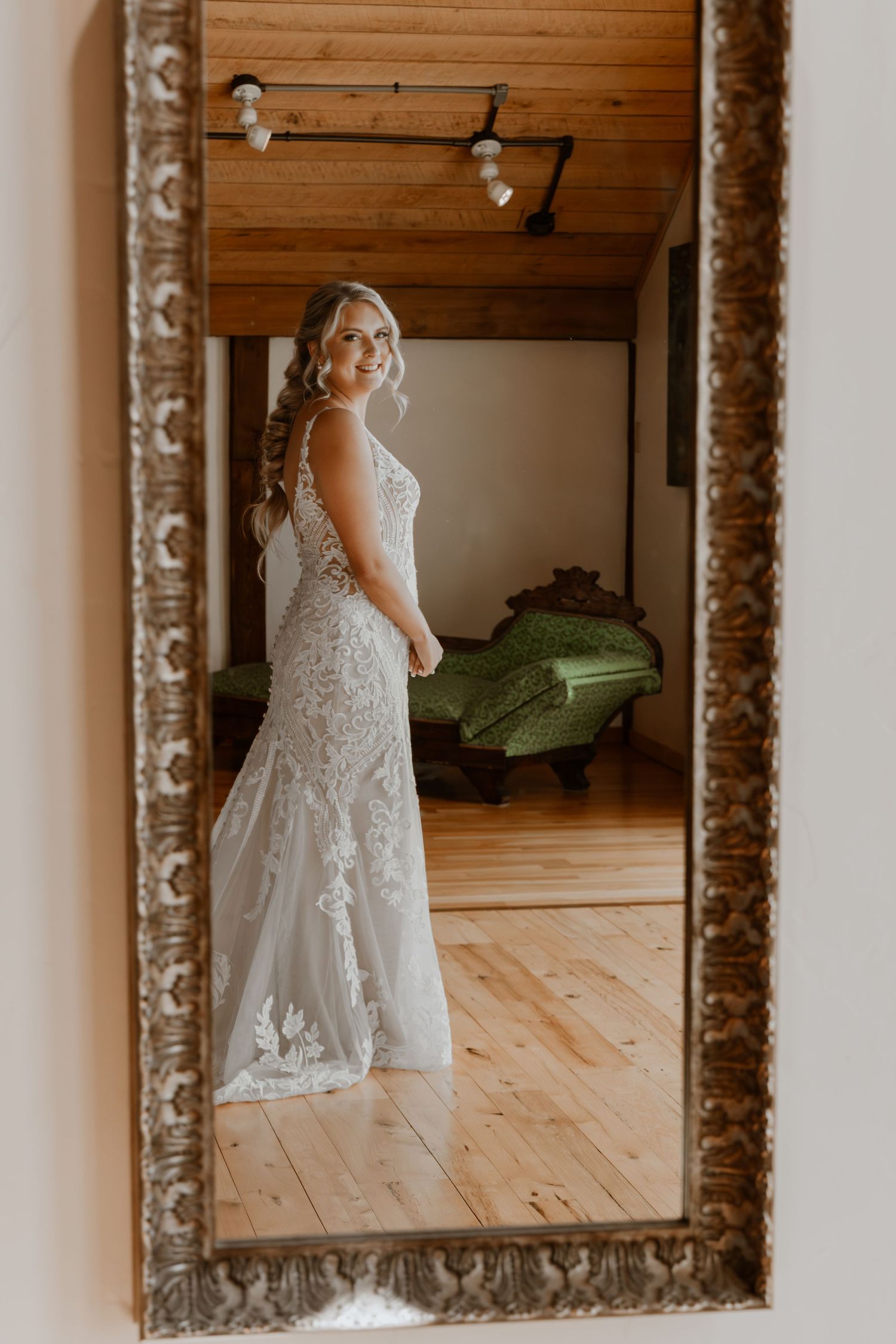 Wedding dress reflection series in ornate vintage mirror against wooden wall.