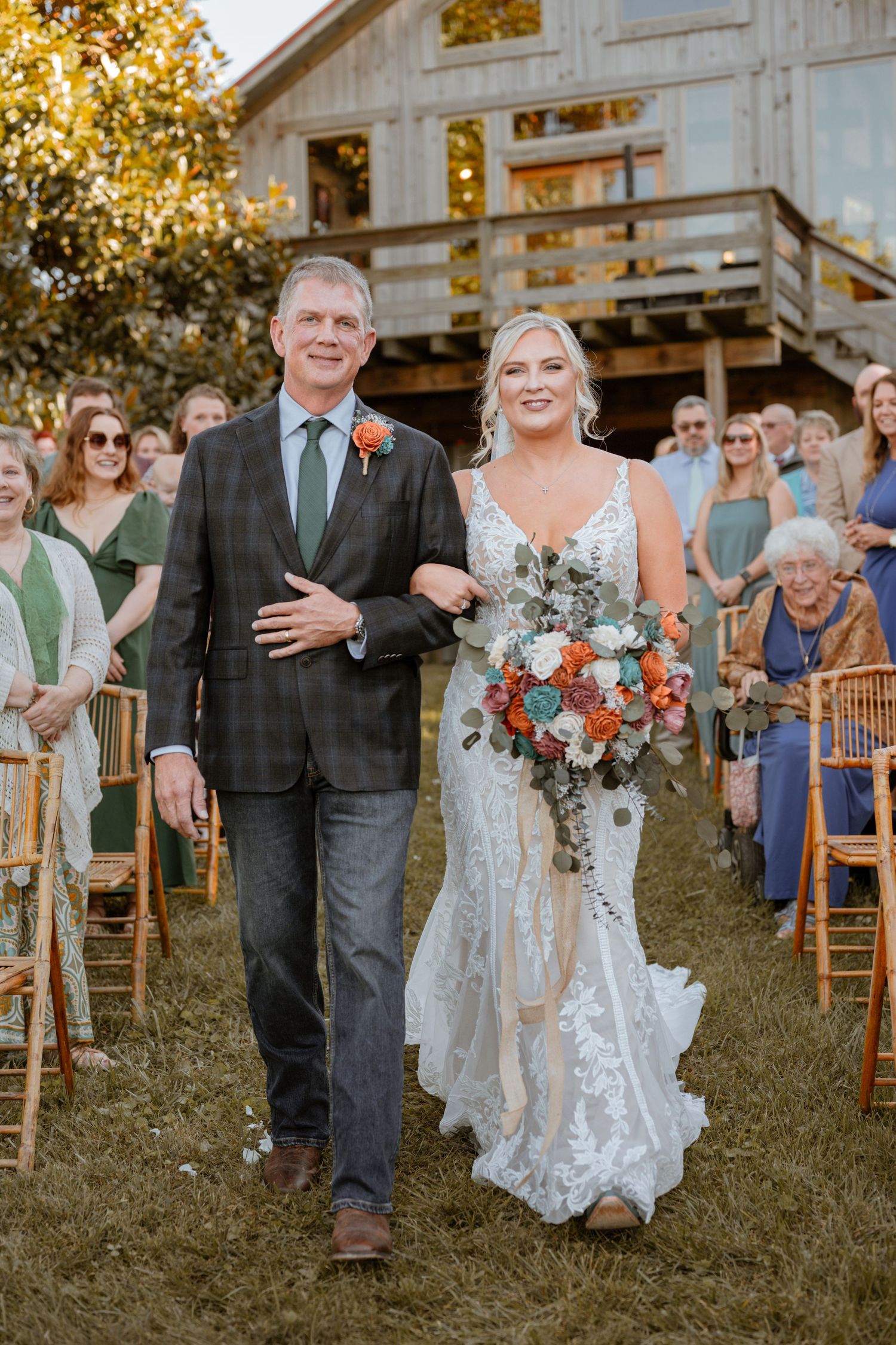 Rustic barn wedding ceremony with guests seated outdoors in autumn.