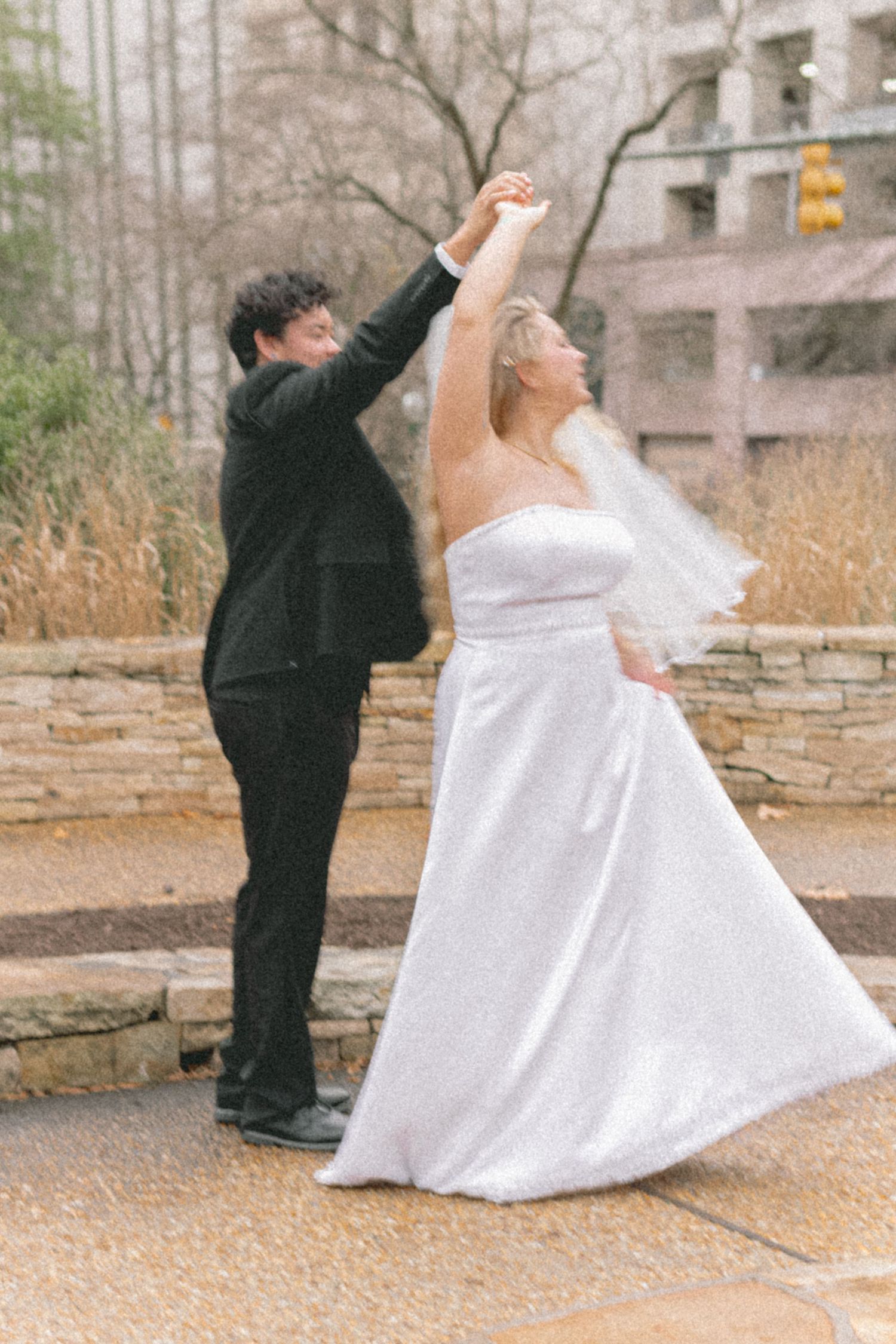 A series of wedding photos captures a couple dancing gracefully against a stone wall backdrop.
