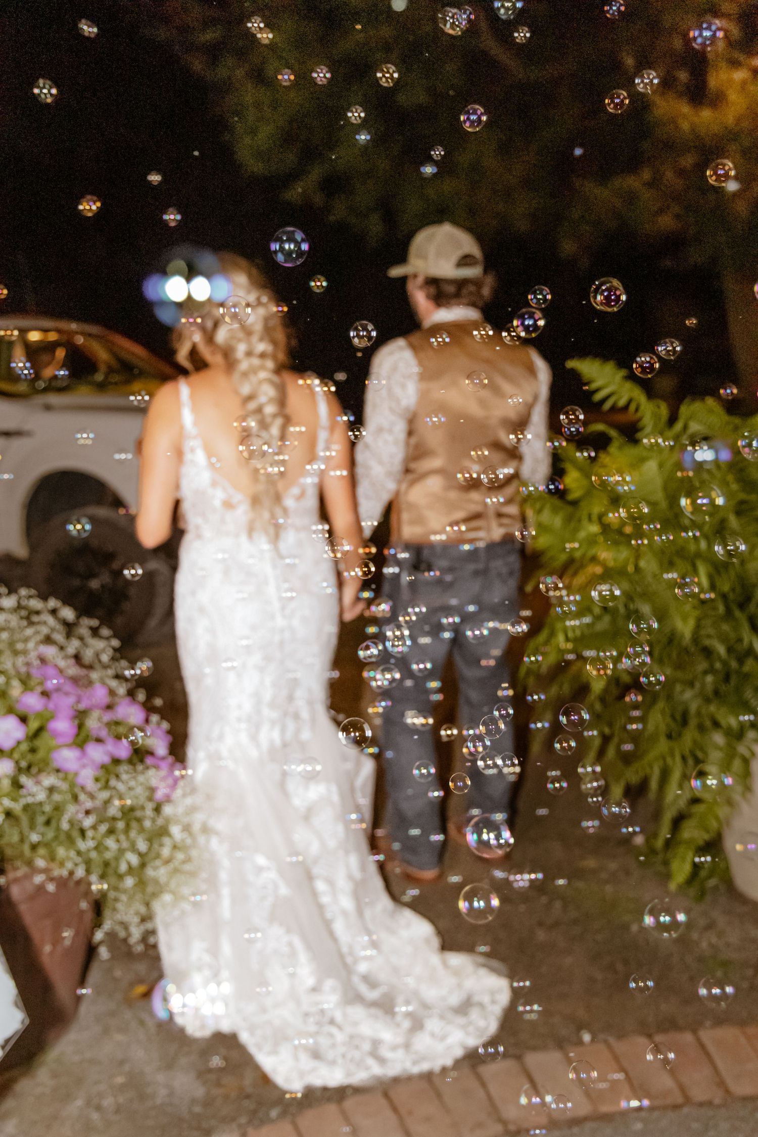 Bride and groom walk hand-in-hand through a magical bubble send-off at their outdoor evening wedding reception.