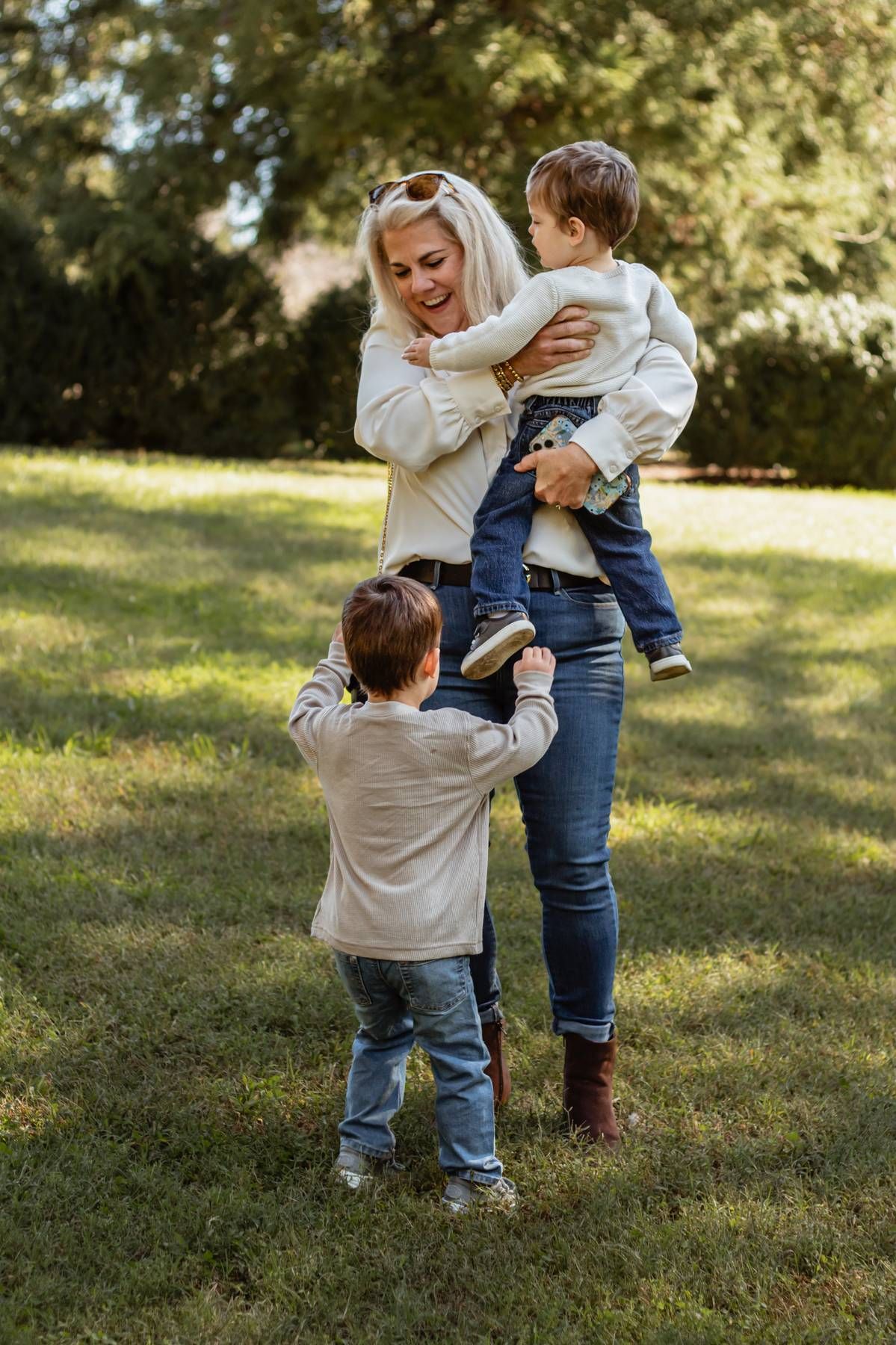 Parent and children share a tender moment playing together on a sunny day in the park.