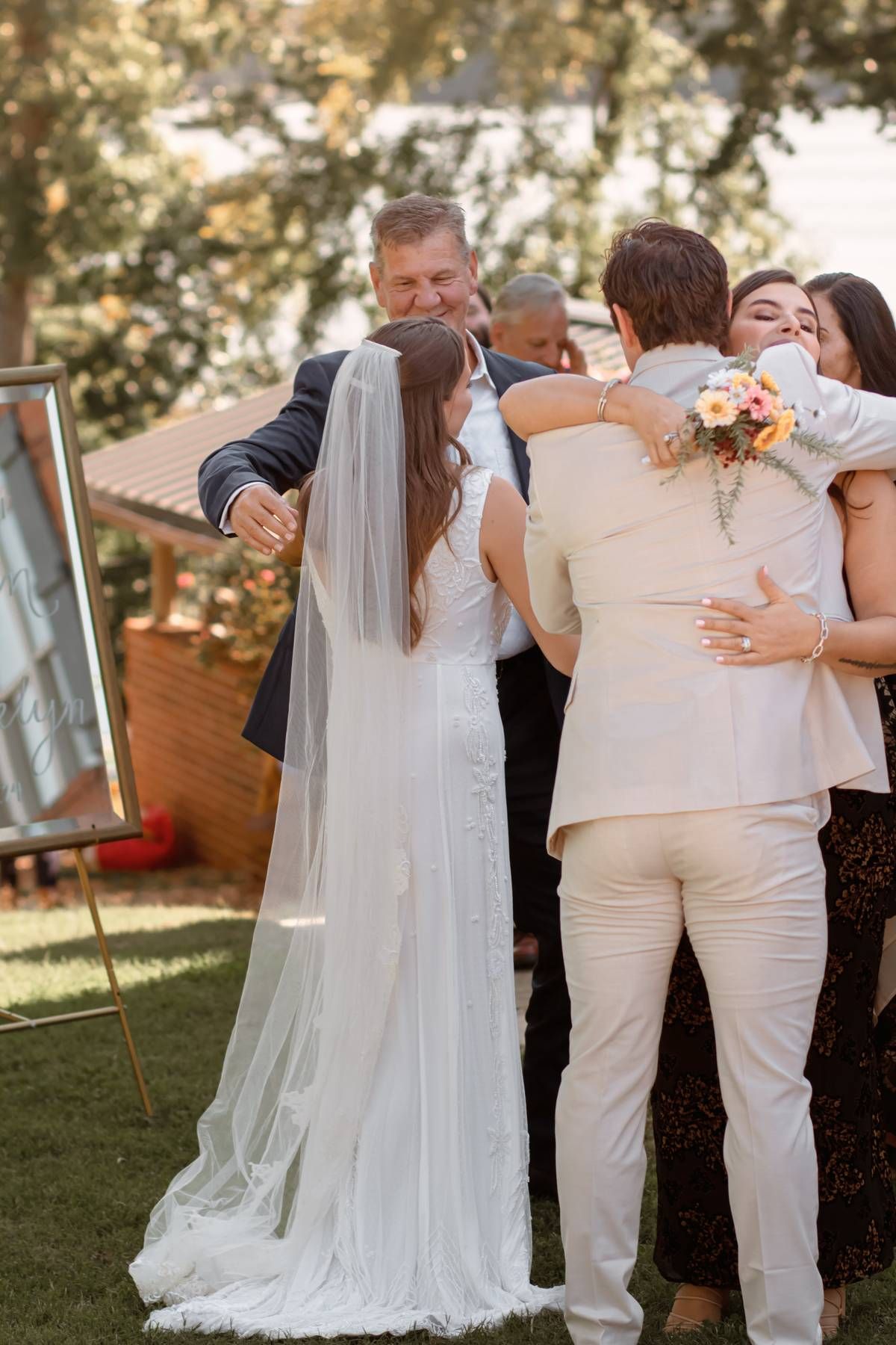 A joyful wedding celebration with family embracing outdoors.