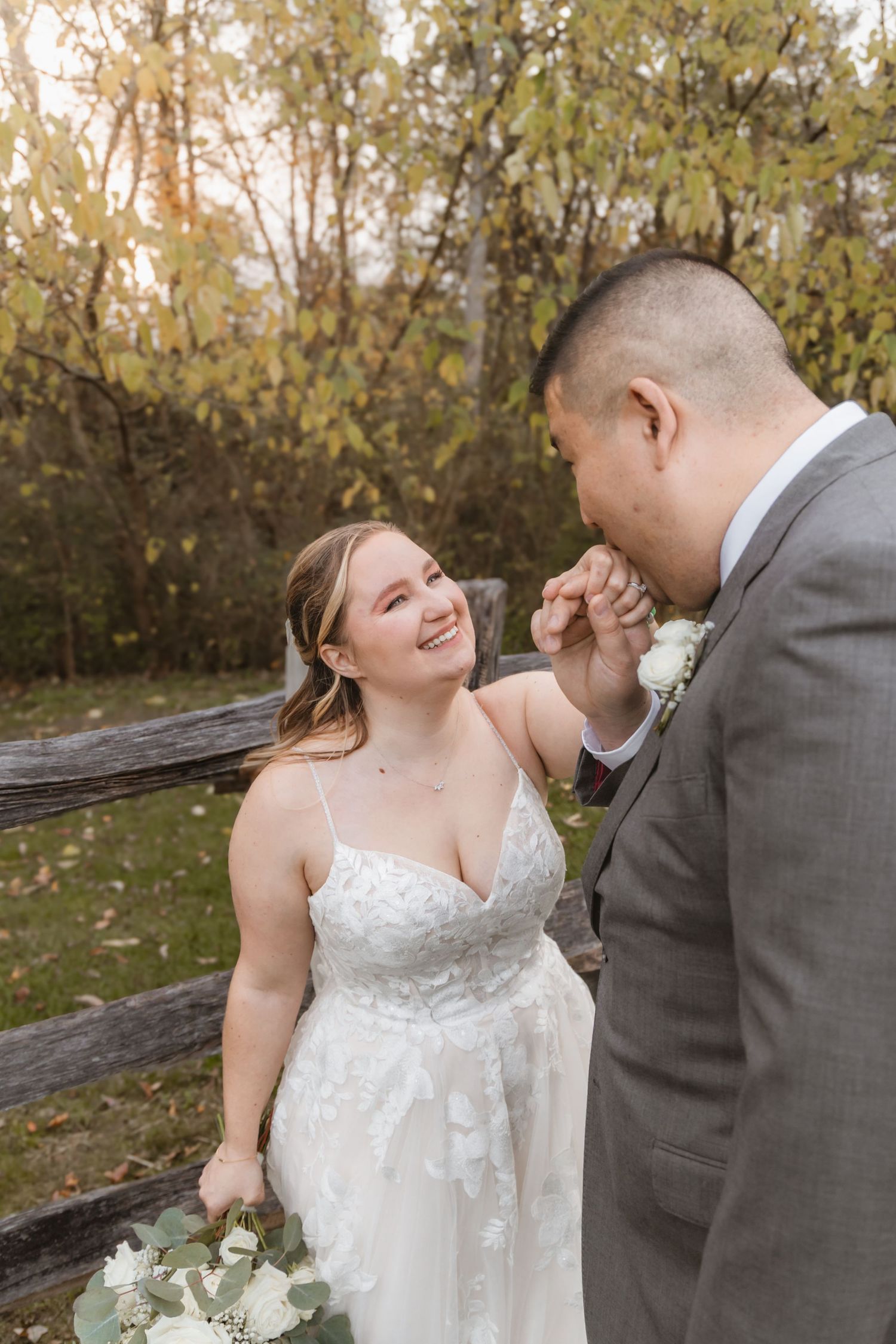 Joyful wedding moment captured outdoors with autumn foliage in background.