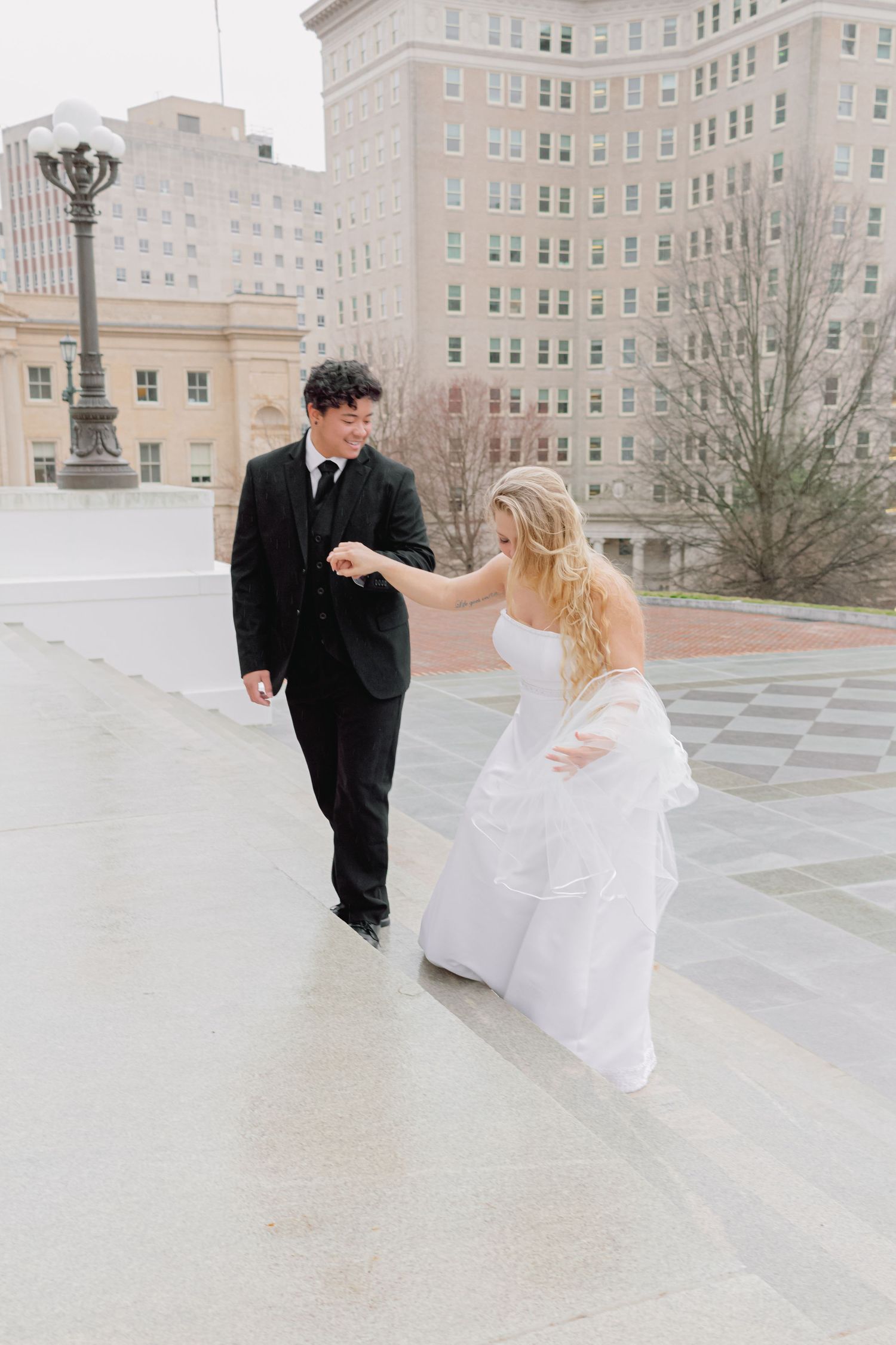 Playful newlyweds dance and twirl on a grand plaza surrounded by classical architecture.