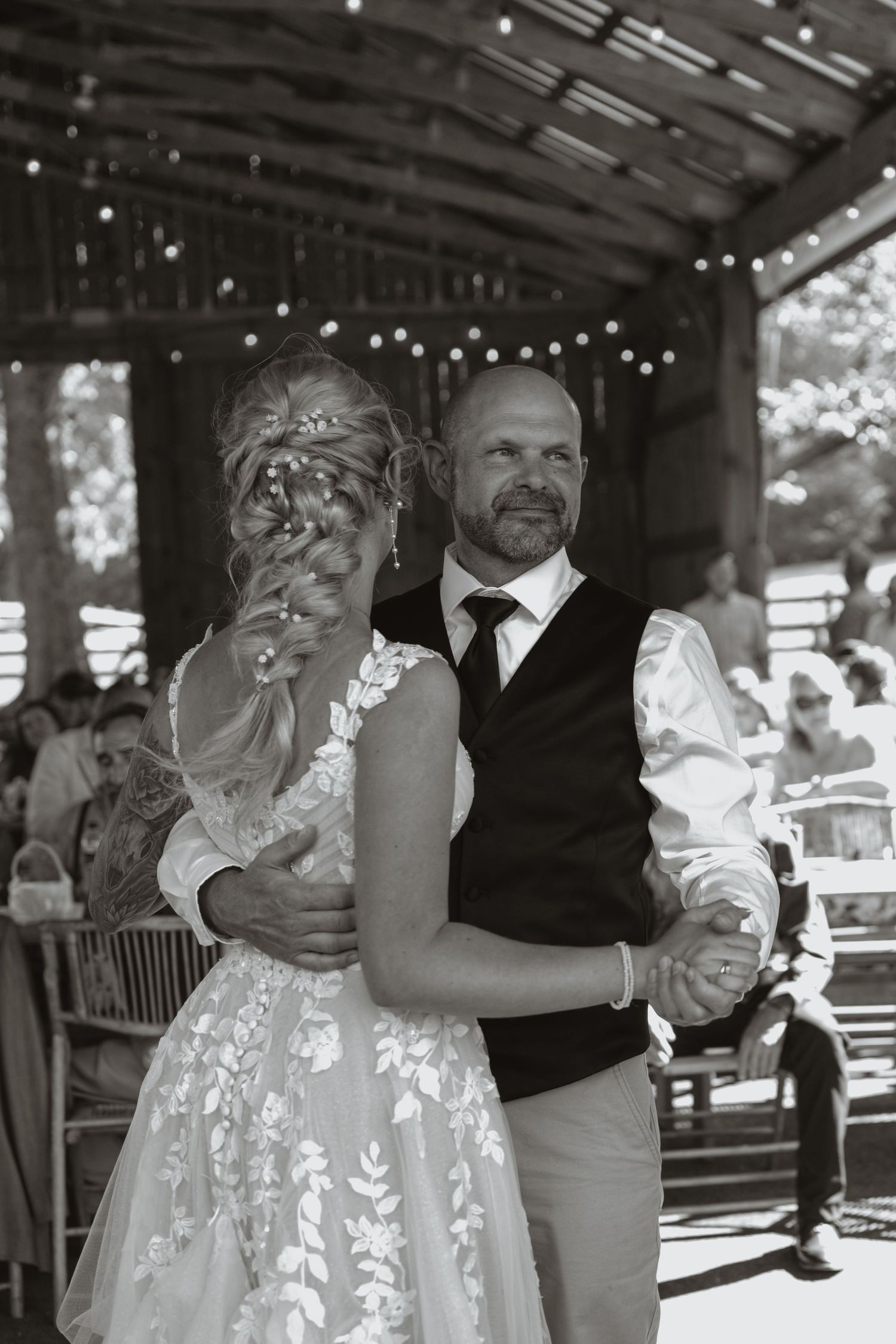 Black and white photo of a bride and groom sharing their first dance at an outdoor wedding reception.