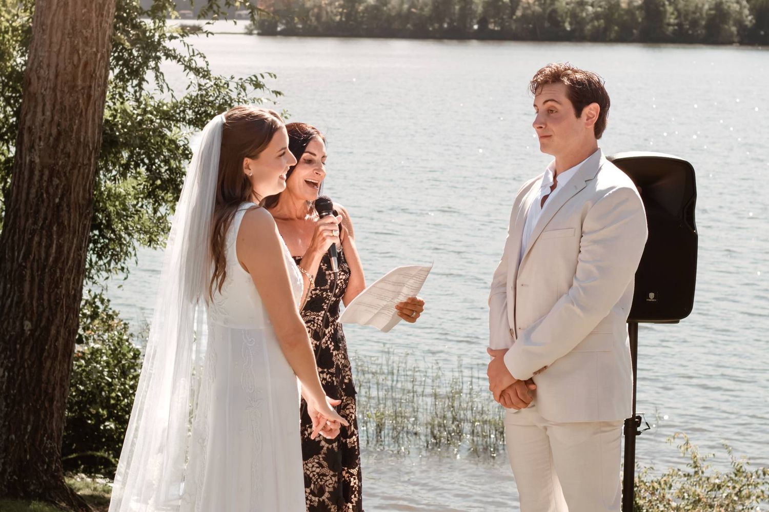 Wedding ceremony sequence showing tender moments between a couple and officiant beside a lake.