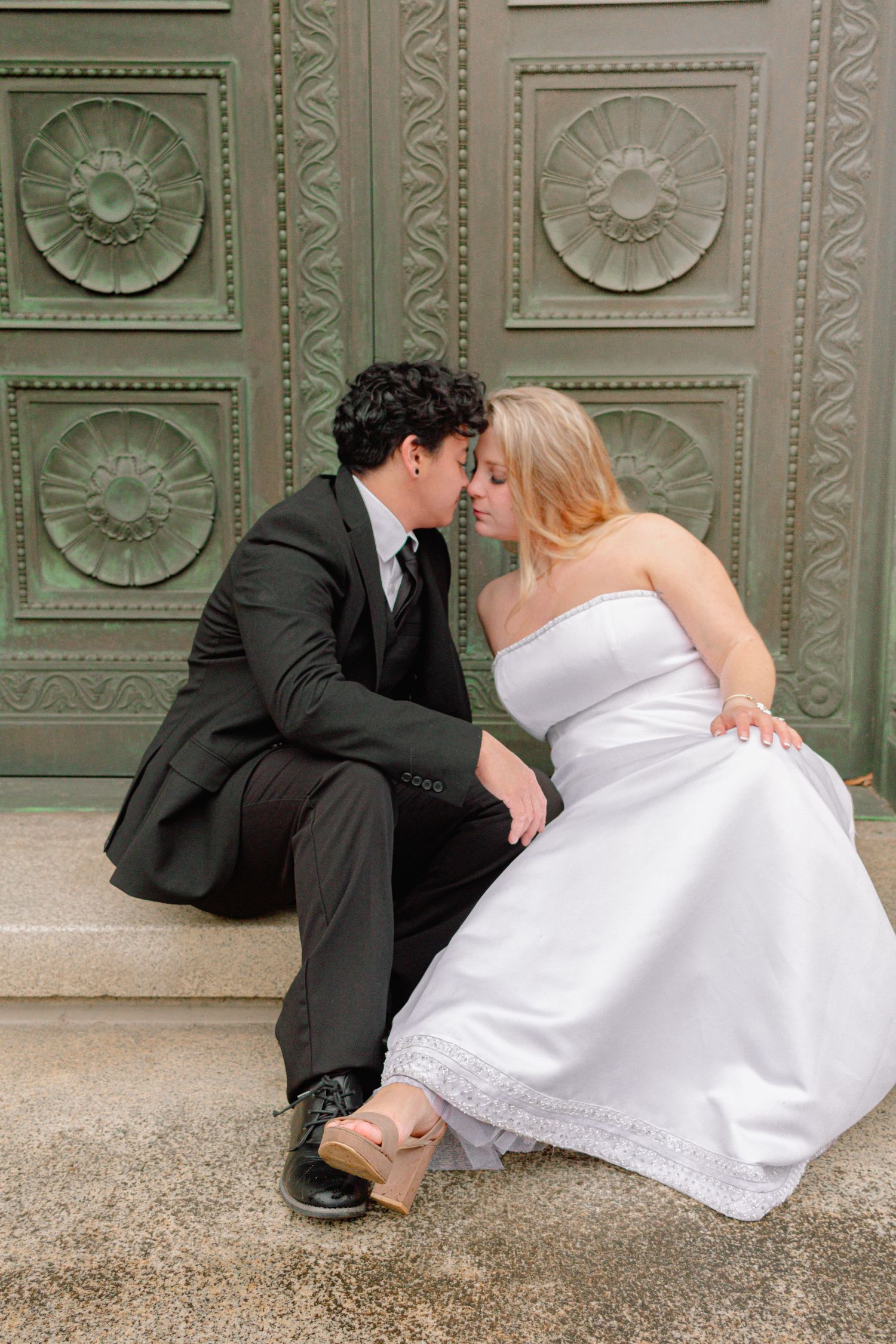 Wedding couple shares romantic moments against an ornate architectural background.
