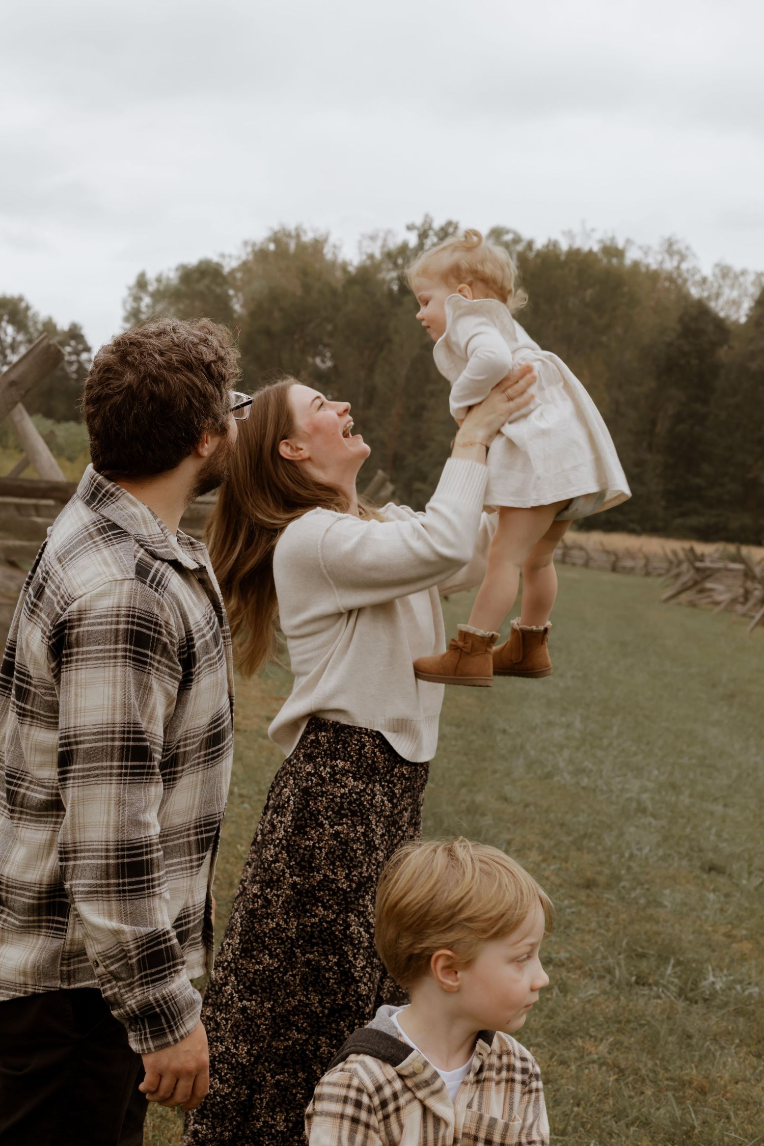 Playful family moments captured during outdoor photoshoot in natural setting.