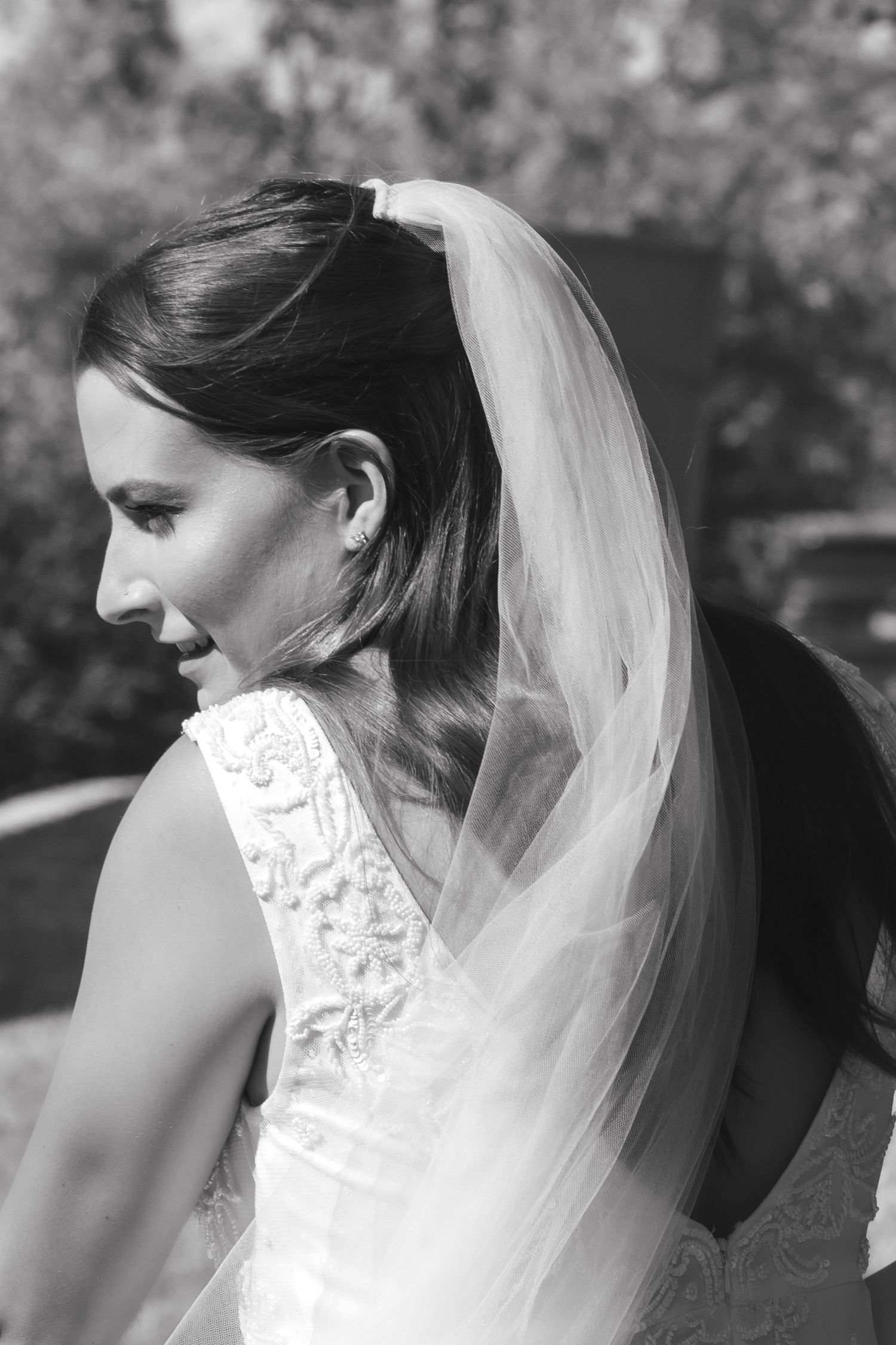 Close-up profile view of a bride wearing a delicate lace veil in natural lighting.