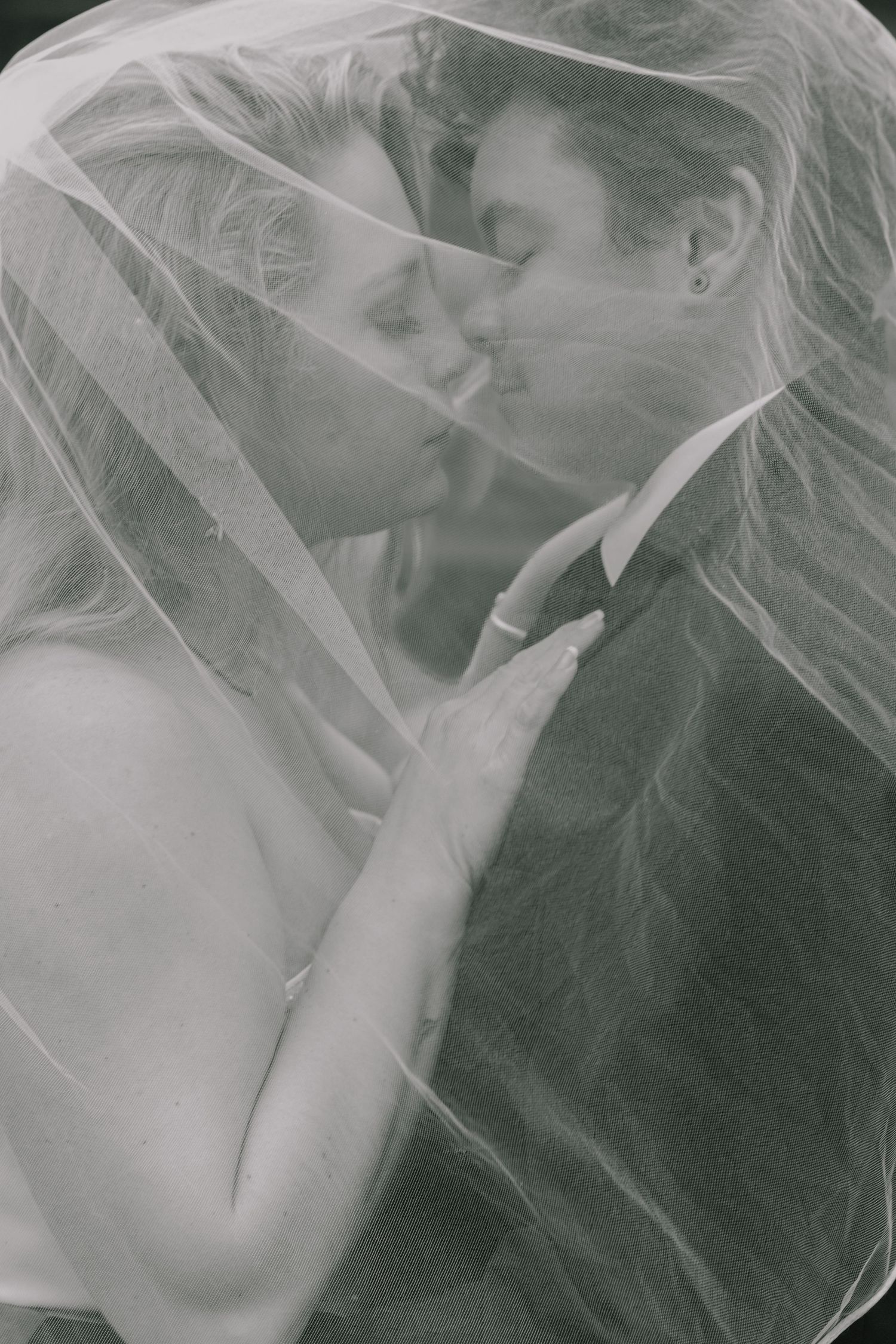 Ethereal black and white wedding portraits capture intimate moments through delicate veil.