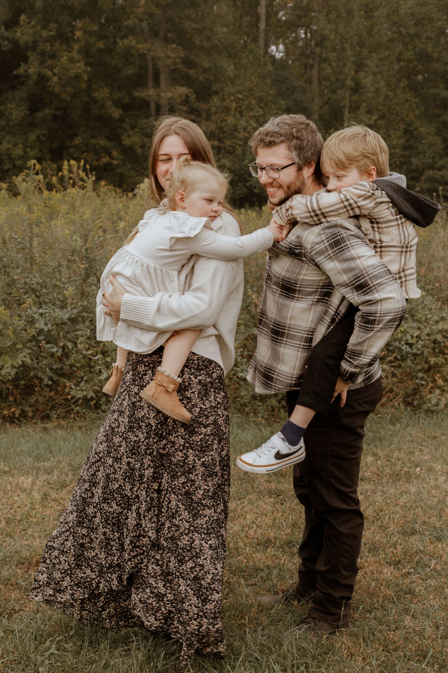 A playful family moment captured outdoors with children reaching across to each other in a natural setting.