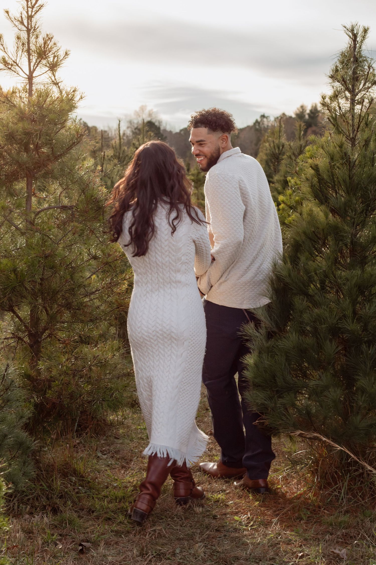 Couple sharing an intimate moment among pine trees during a photoshoot.