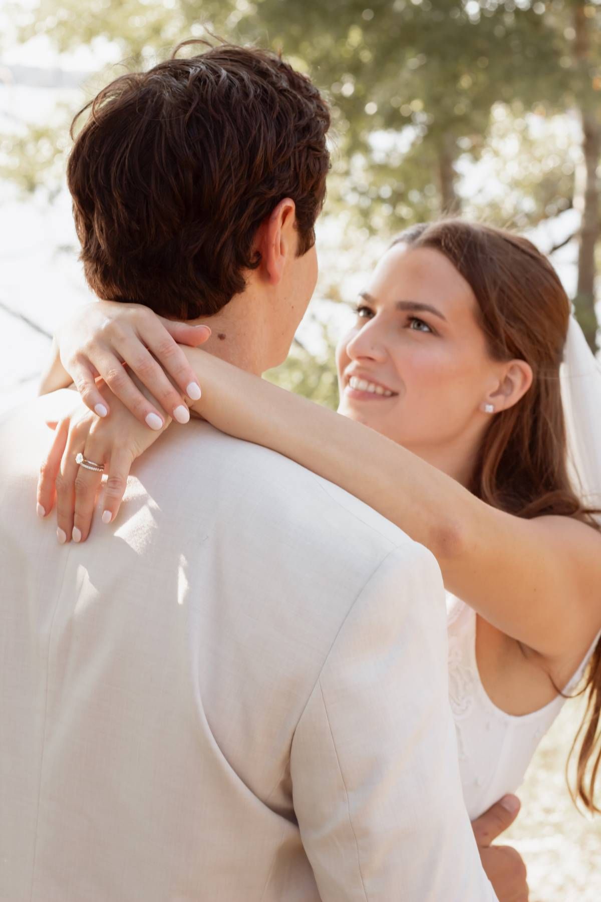 Tender embrace captured in soft sunlight during wedding celebration.
