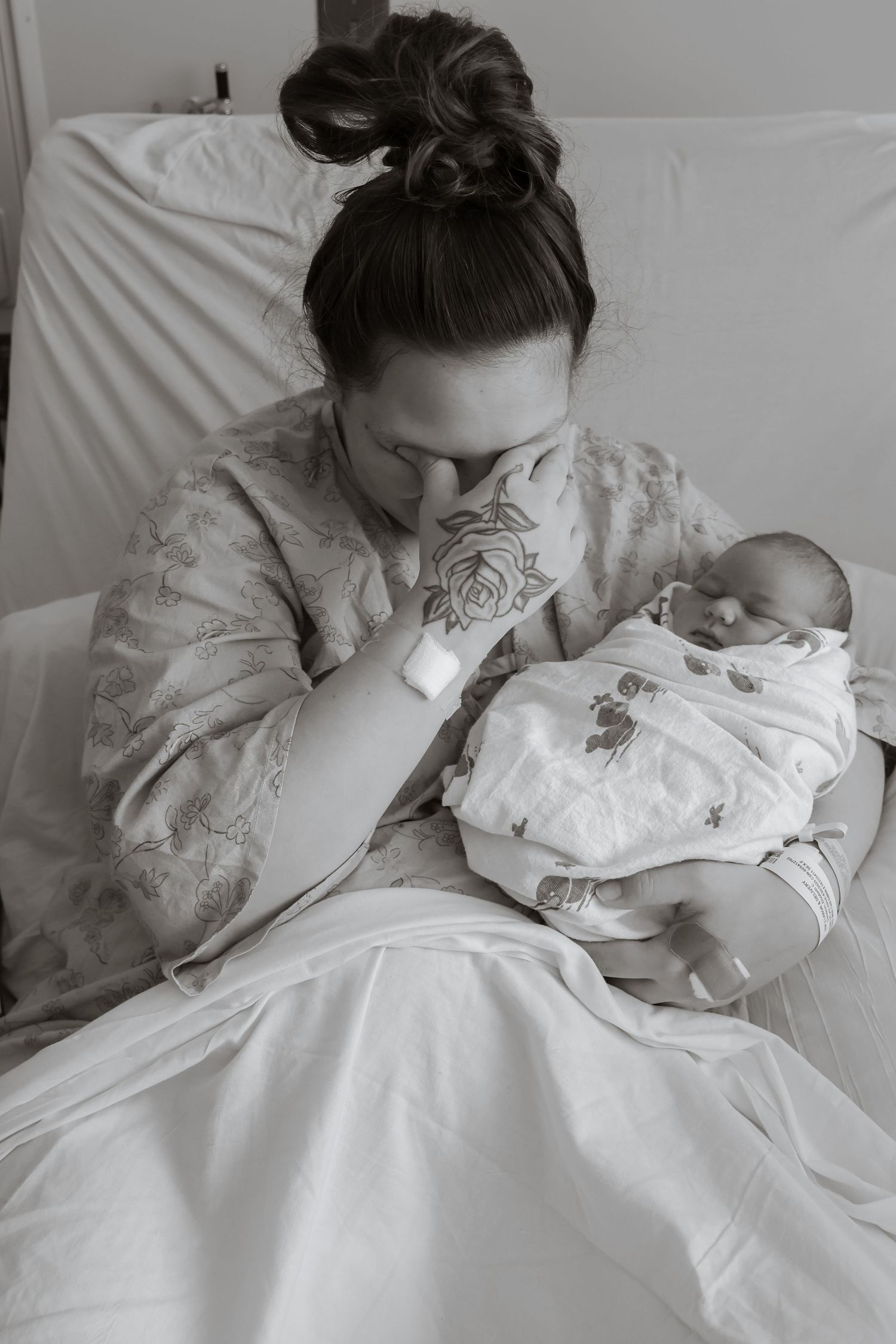Mother in white dress tenderly bonding with newborn baby in bed.