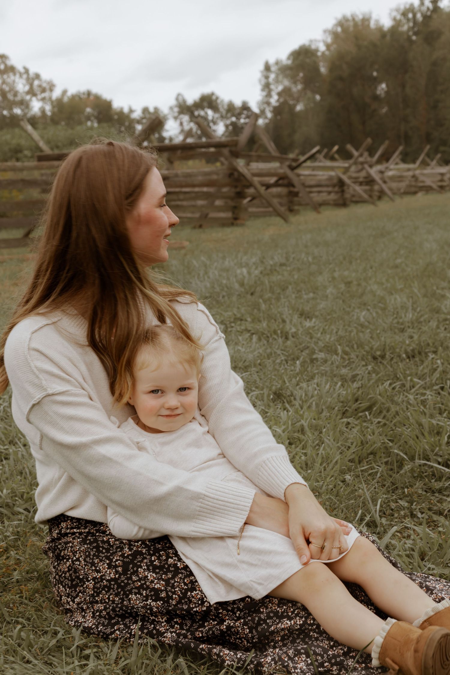 Relaxed family moment captured in grassy field during outdoor photo session.
