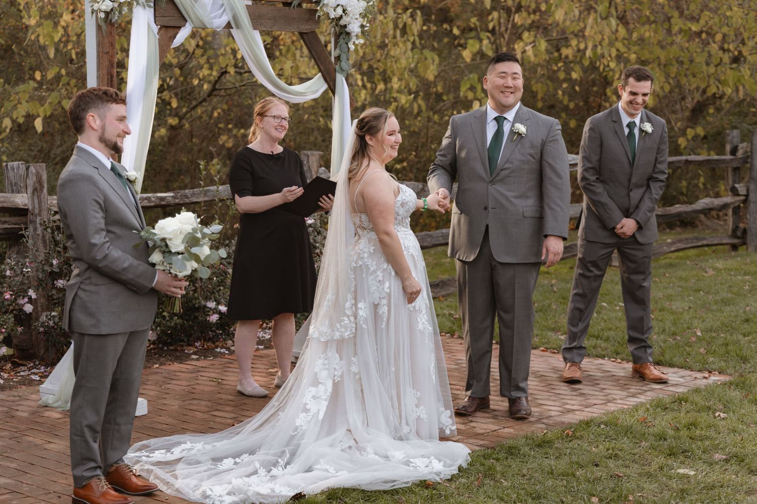 Outdoor autumn wedding ceremony with white chairs and floral arch decorations.