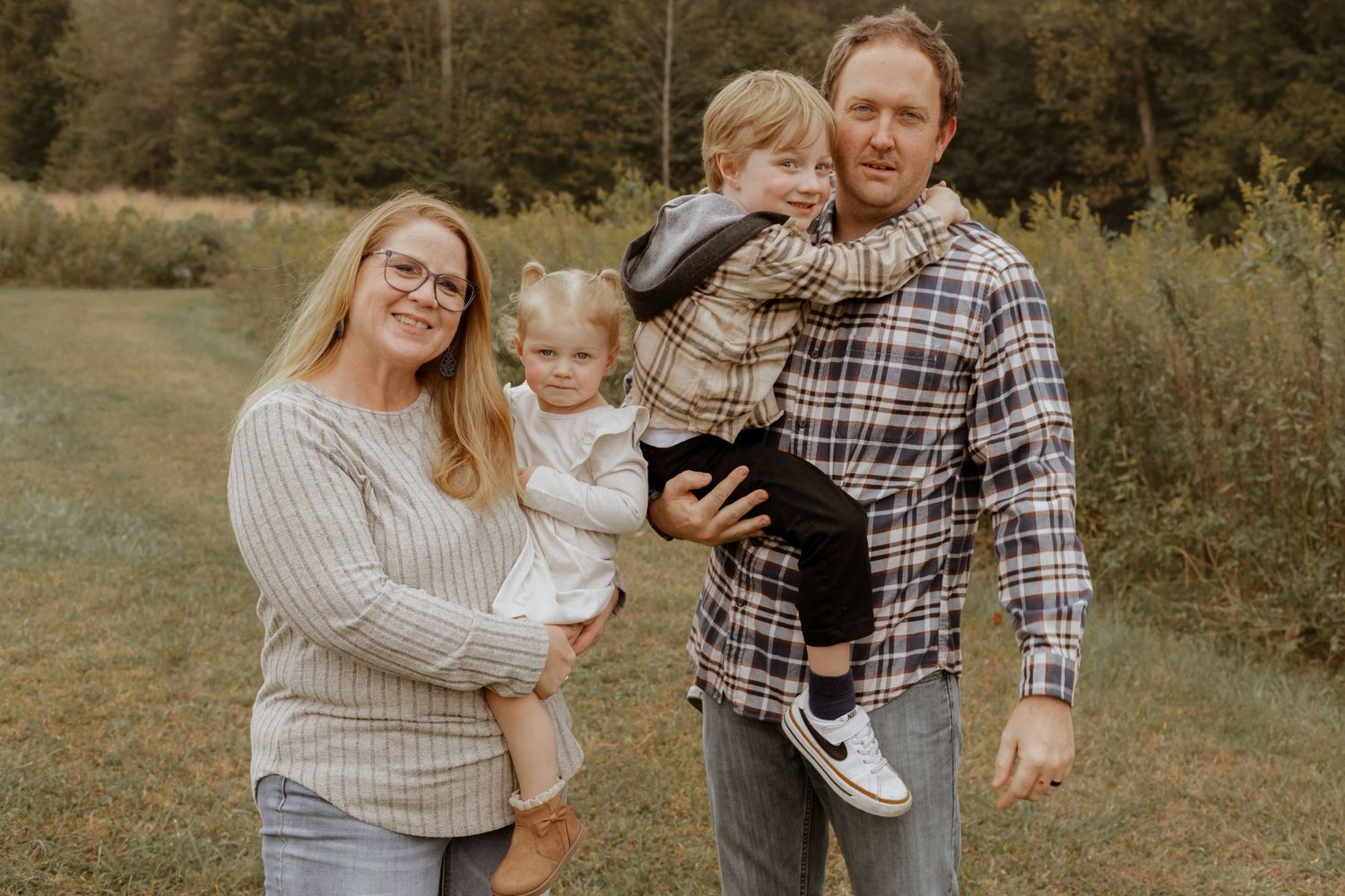 Family members share joyful moments together during an autumn photoshoot in a field.