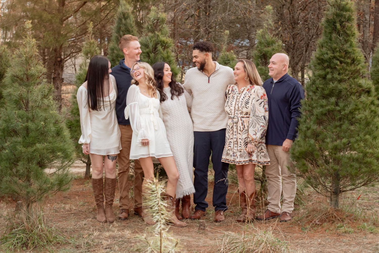 Family group photo session among pine trees with coordinated casual outfits.