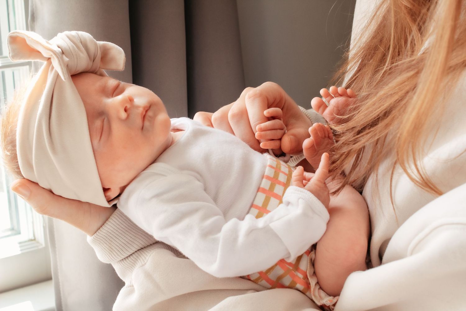 Tender moments captured between parent and newborn in soft white clothing.