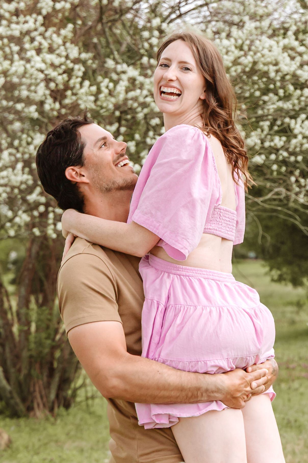 Joyful moment captured in outdoor portrait session with pink dress.