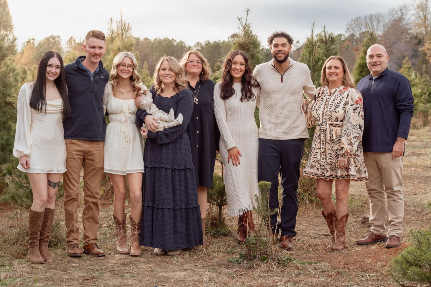 Extended family gathering for outdoor group photos in coordinated neutral outfits.