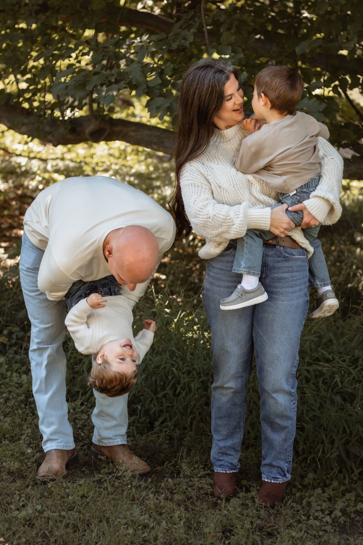 Playful family moment captured outdoors with parents in matching sweaters entertaining their children.
