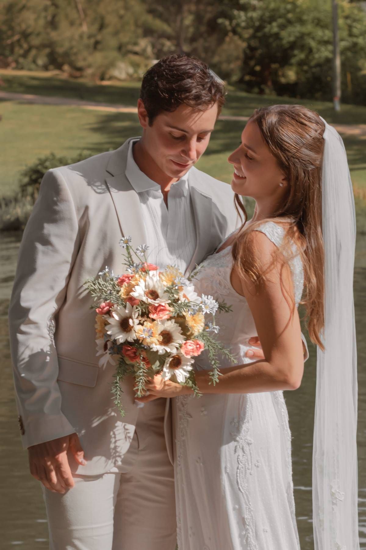 A lakeside wedding moment with a beautiful bouquet of daisies and roses.