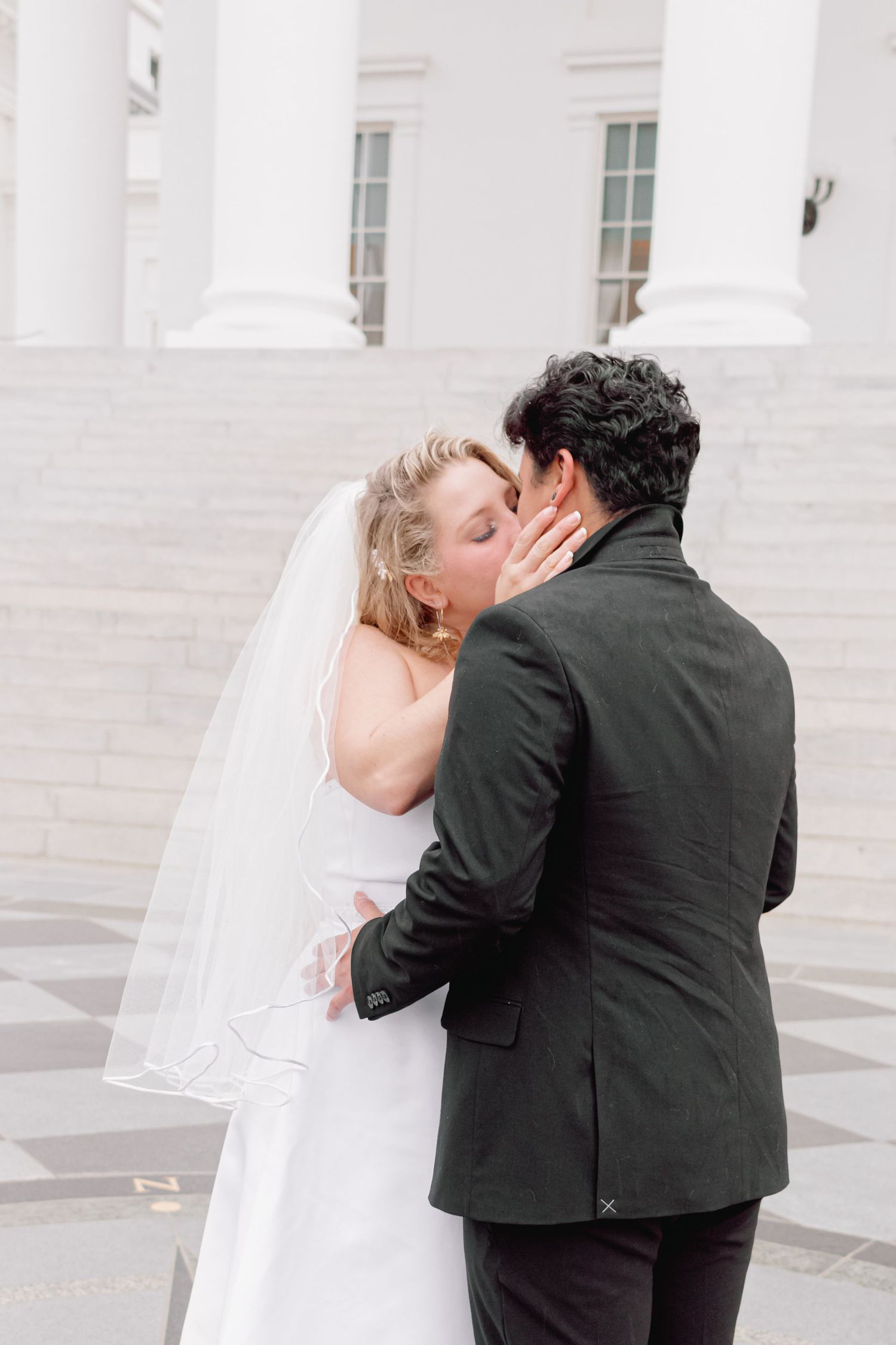 Wedding couple shares a romantic moment on the steps of a historic building.