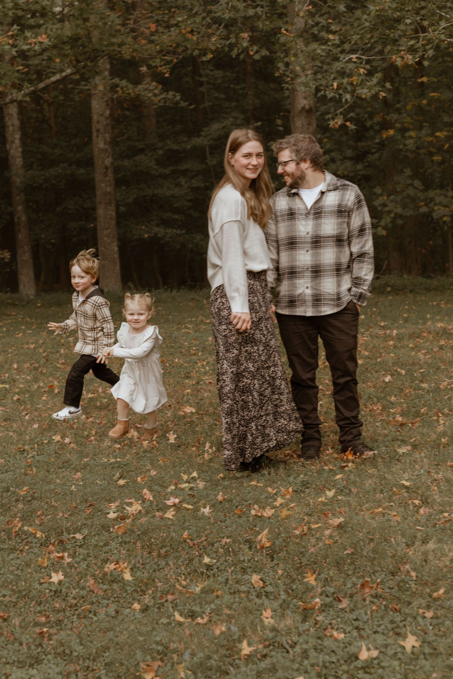 Family enjoying a playful moment together in an autumn forest setting.