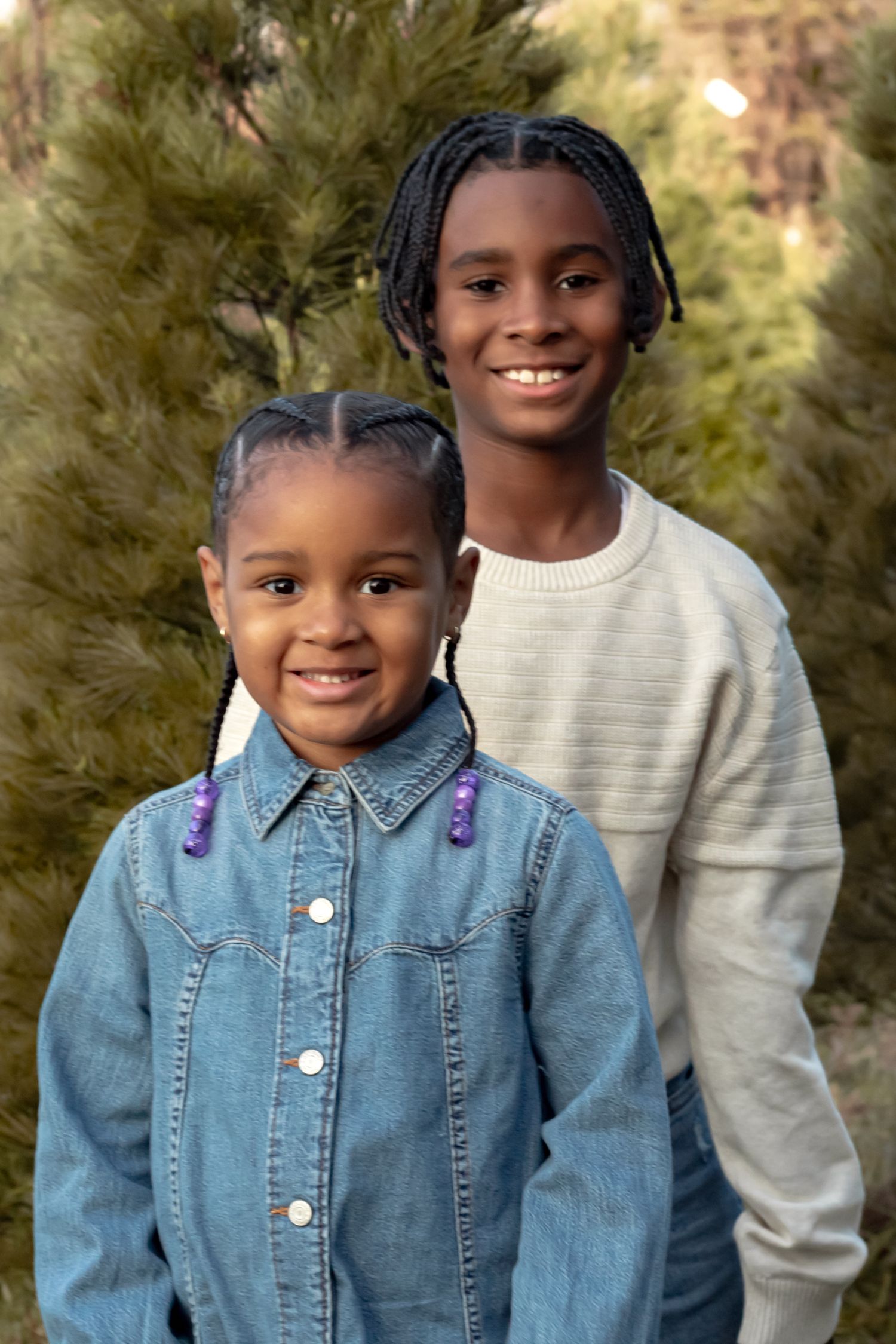 Outdoor portrait series showing bright smiles and denim jacket against evergreen trees.