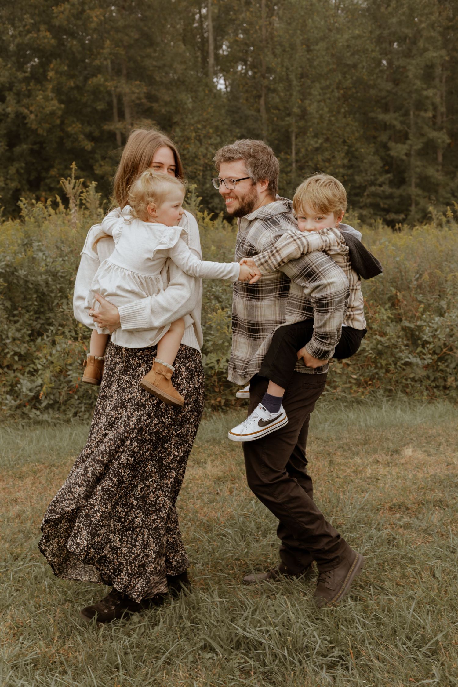 Family playing and dancing together in a natural outdoor setting.