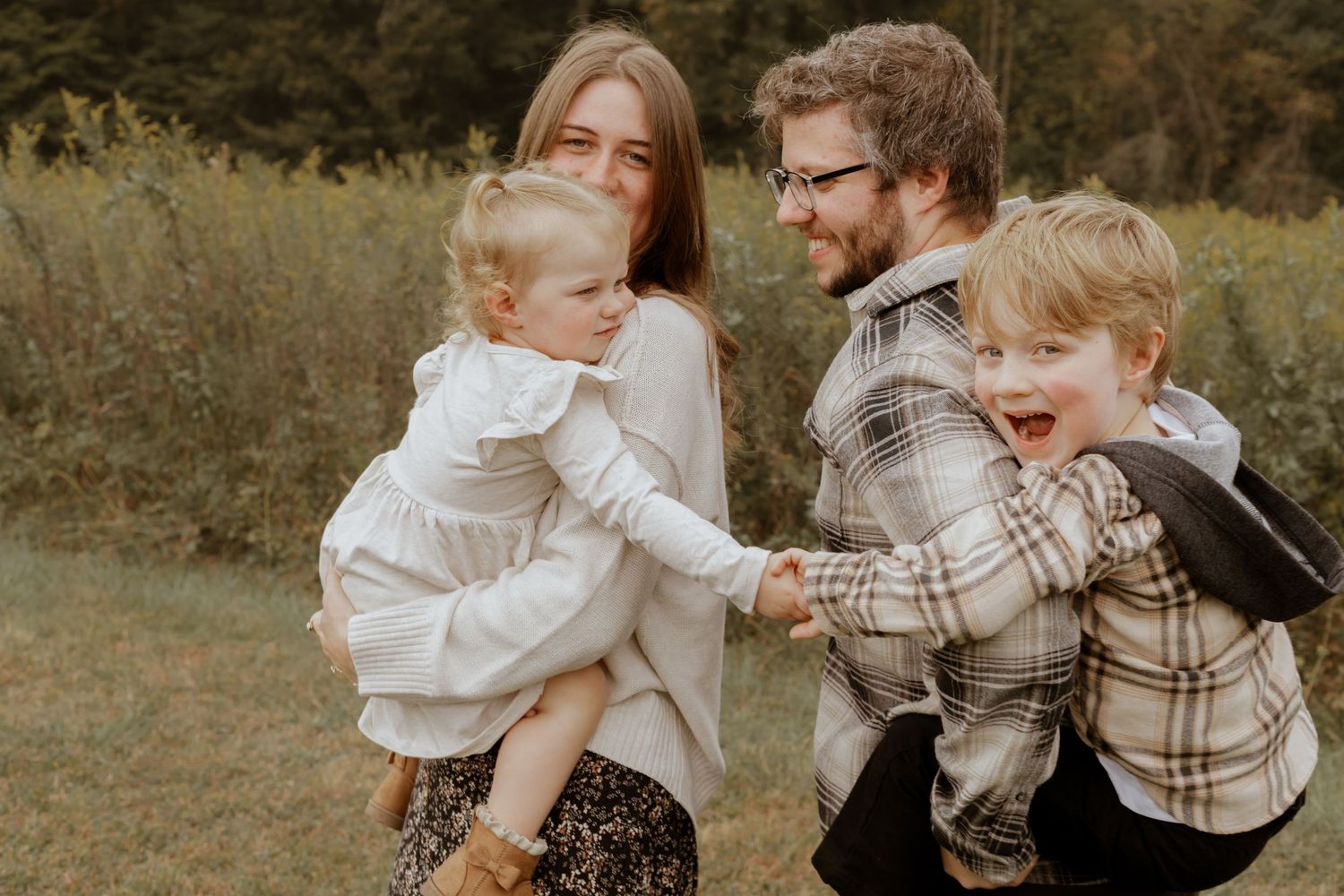 Playful family moment captured outdoors with casual clothing and natural lighting.
