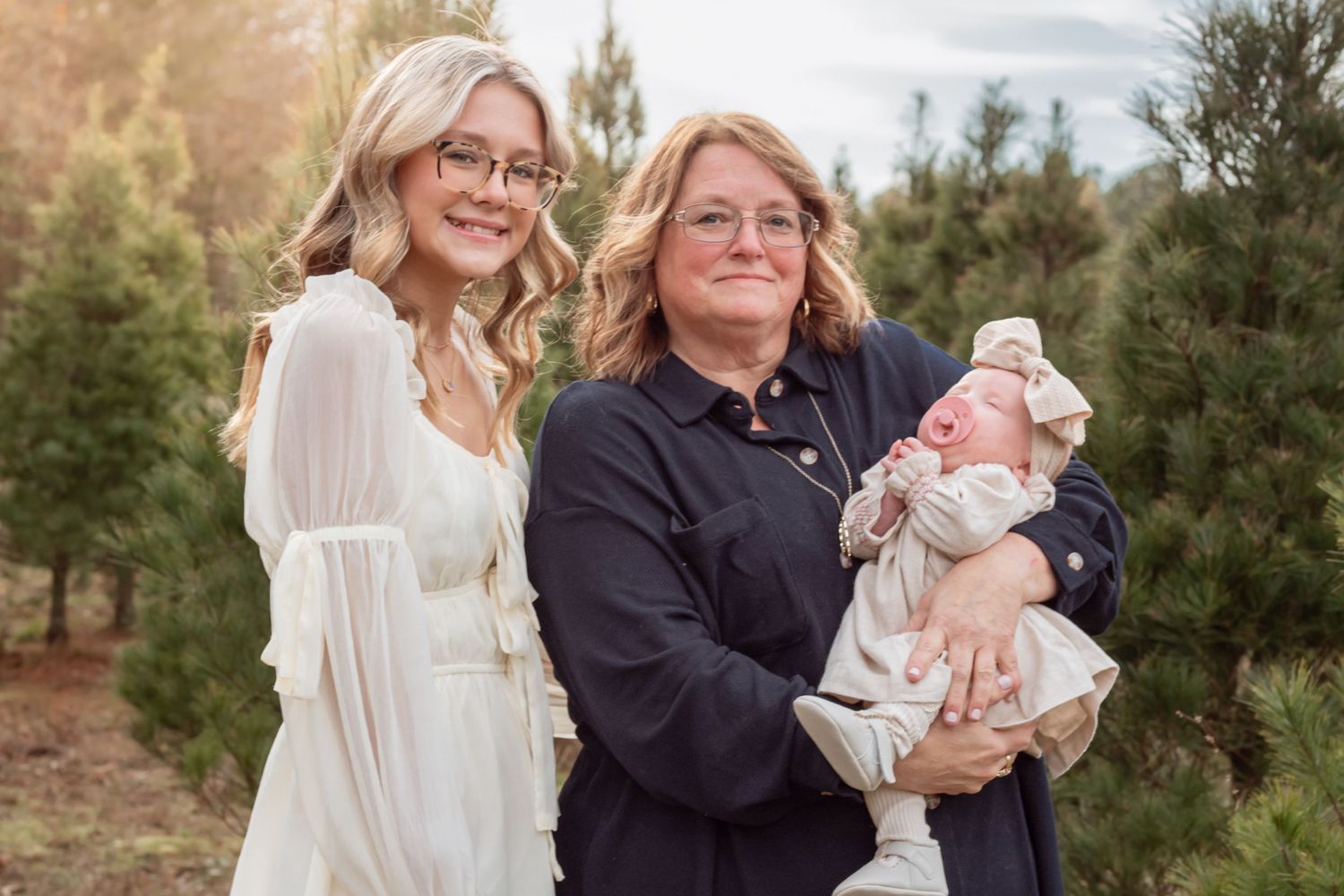 Outdoor family portrait session with newborn baby among pine trees.