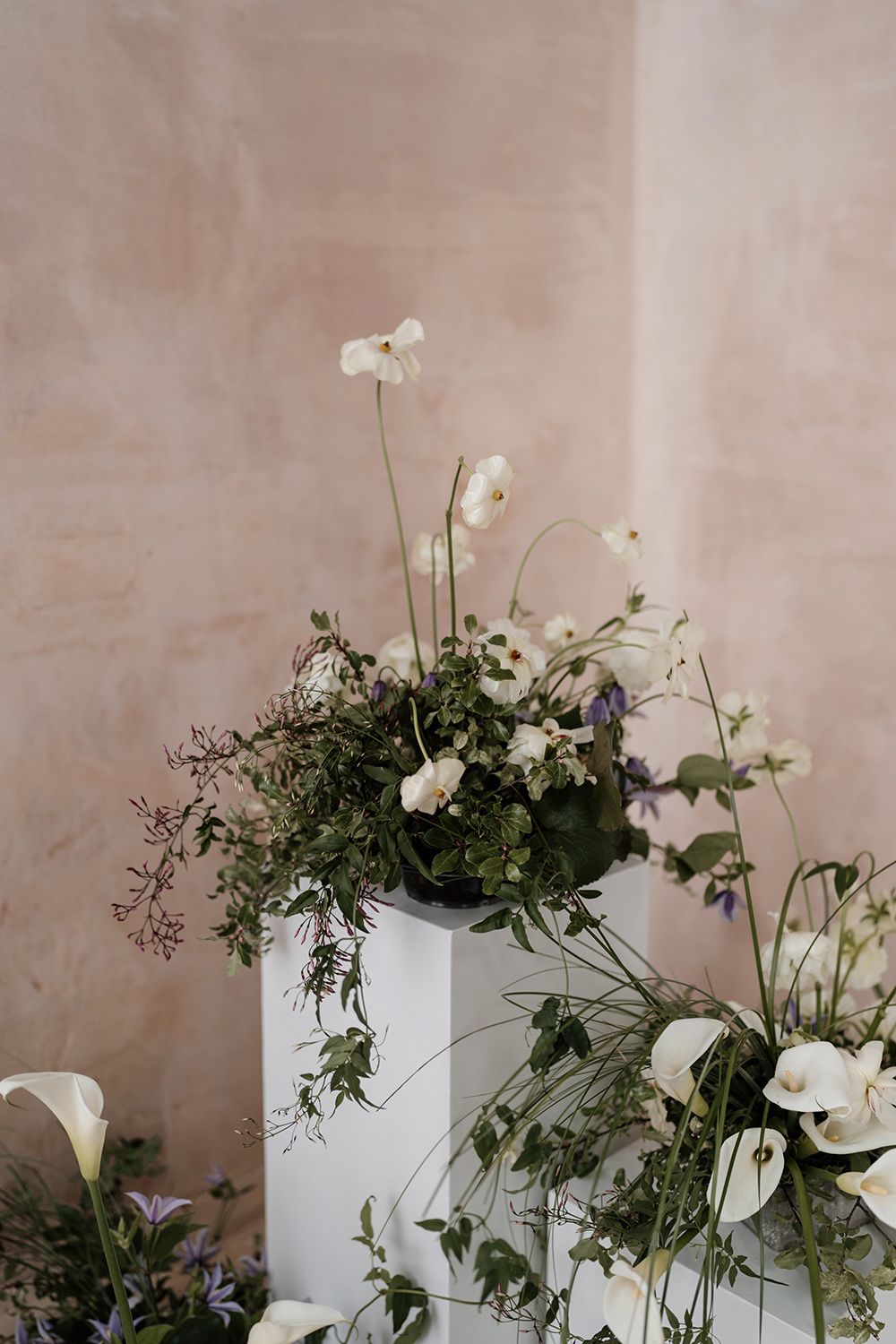 Green and white flowers on a white tower with a limewash wall behind.
