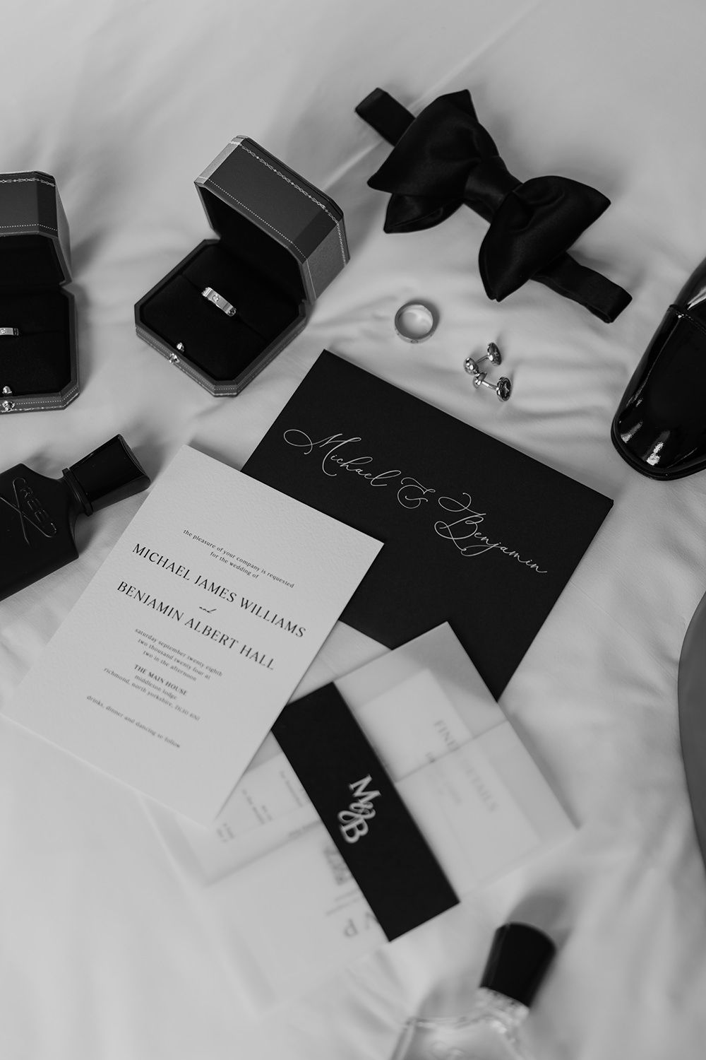 Grooms wedding rings, stationery, shoes, aftershave and wedding rings on a white background.