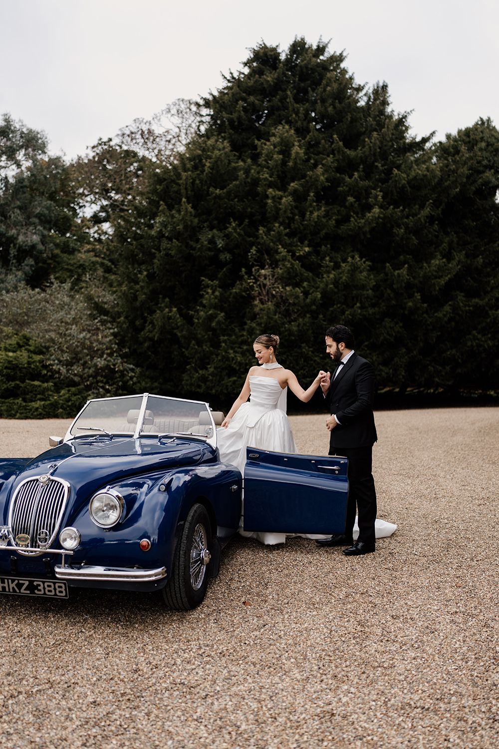 Bride and groom in the grounds at Rise Hall while the bride steps out of a vintage car.