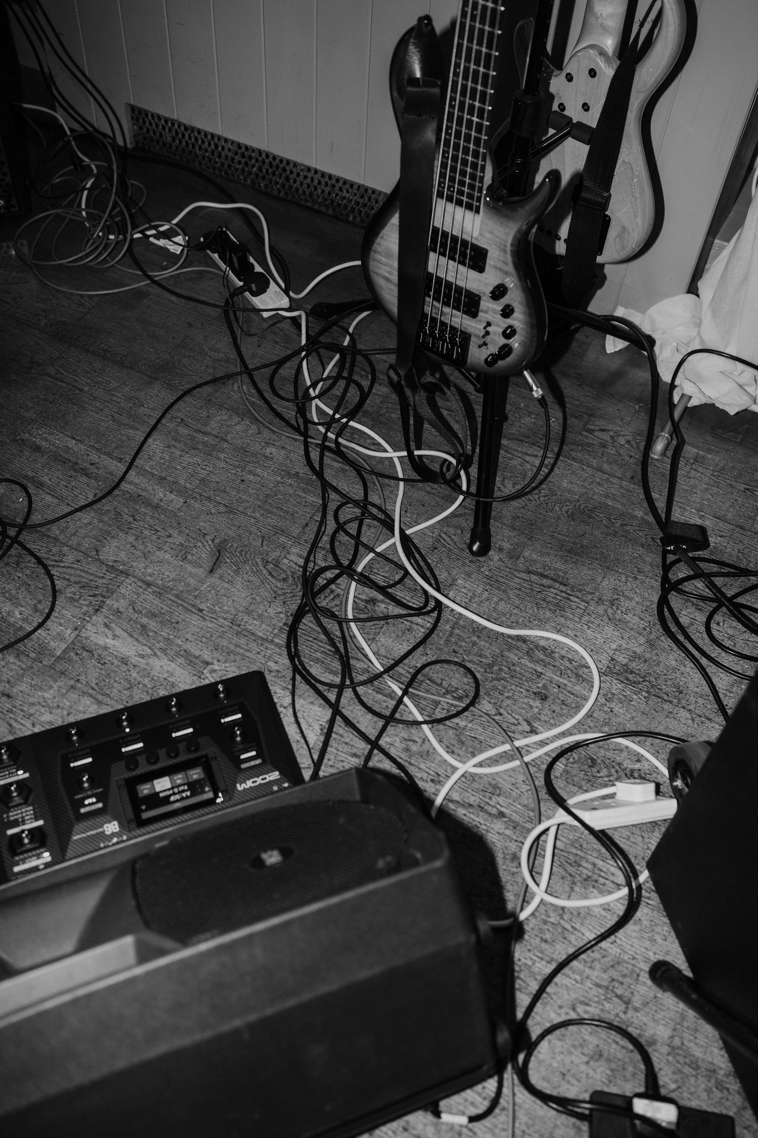 Electric bass guitar with amplifier and cables set up on wooden floor.