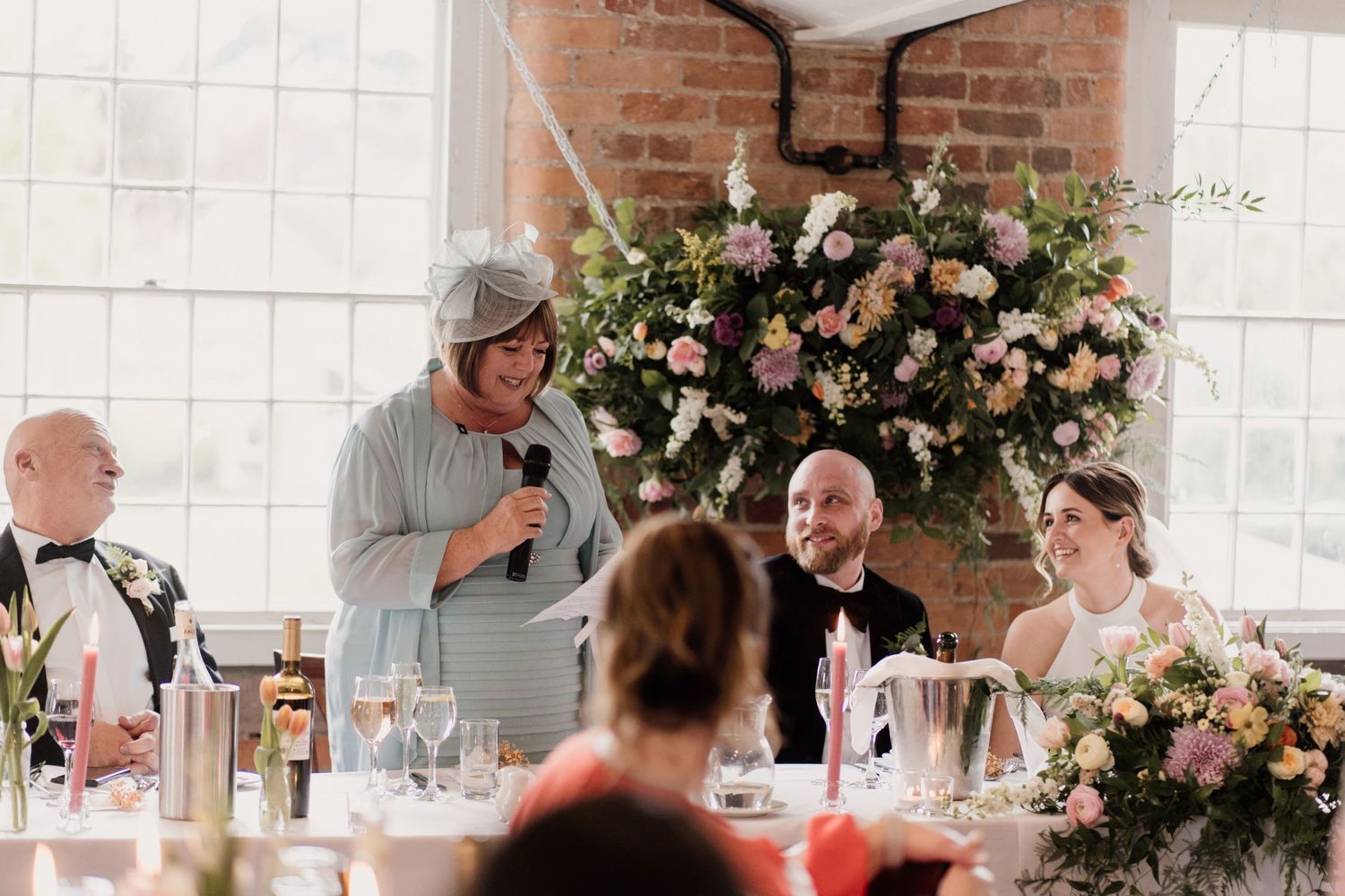 Wedding celebration with floral arrangements and toasts being given during reception dinner.