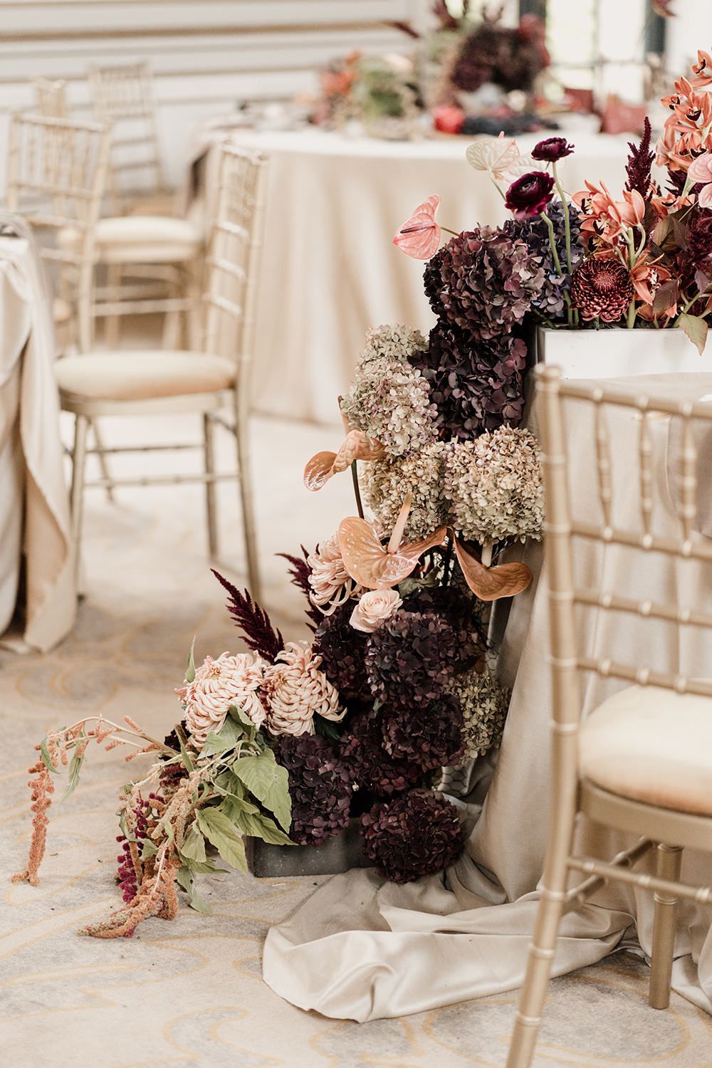 Wedding reception table detail featuring autumnal fabrics, red and burgundy flowers and candles.