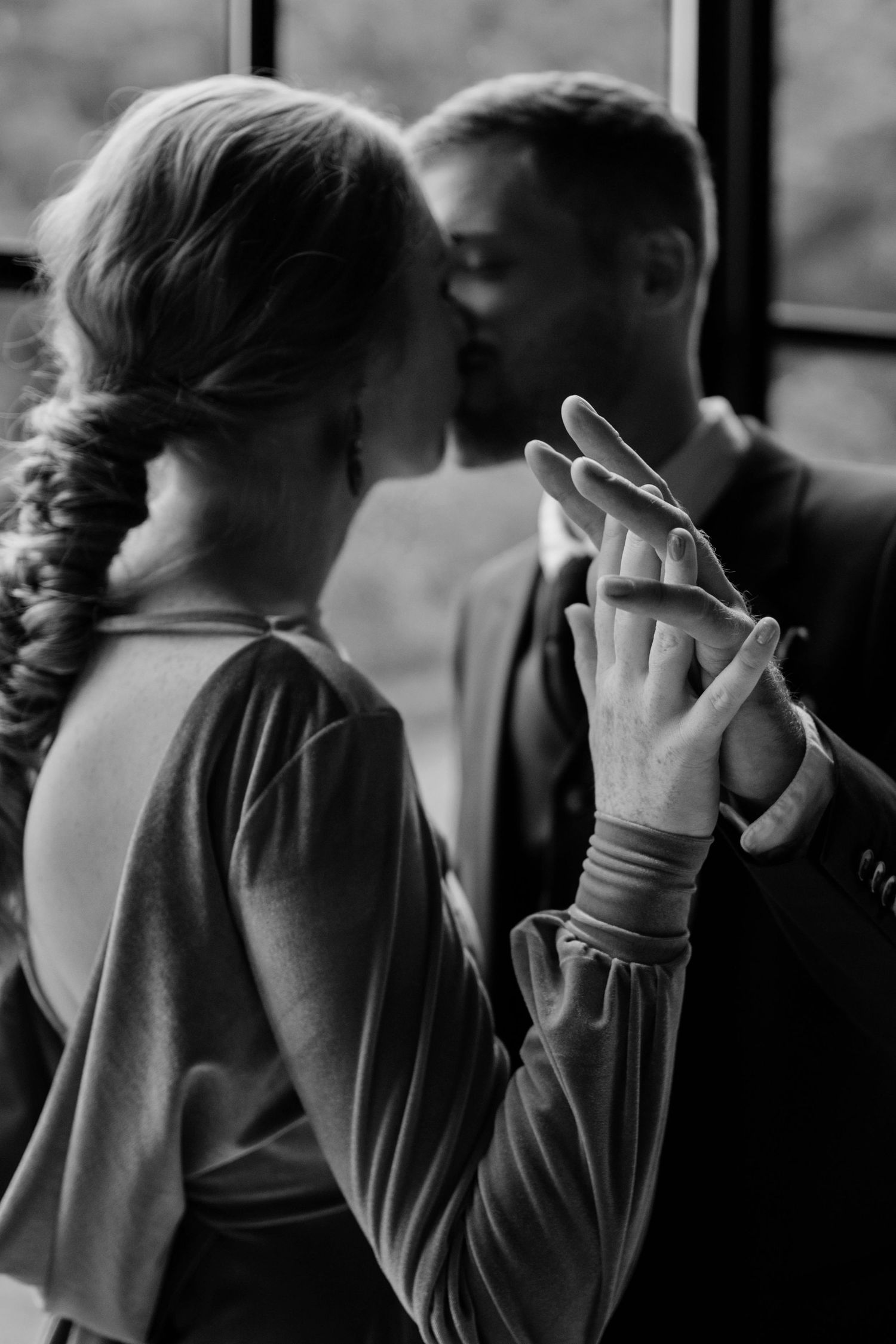 Close up of a couples hands wile their faces kissing are in the background.
