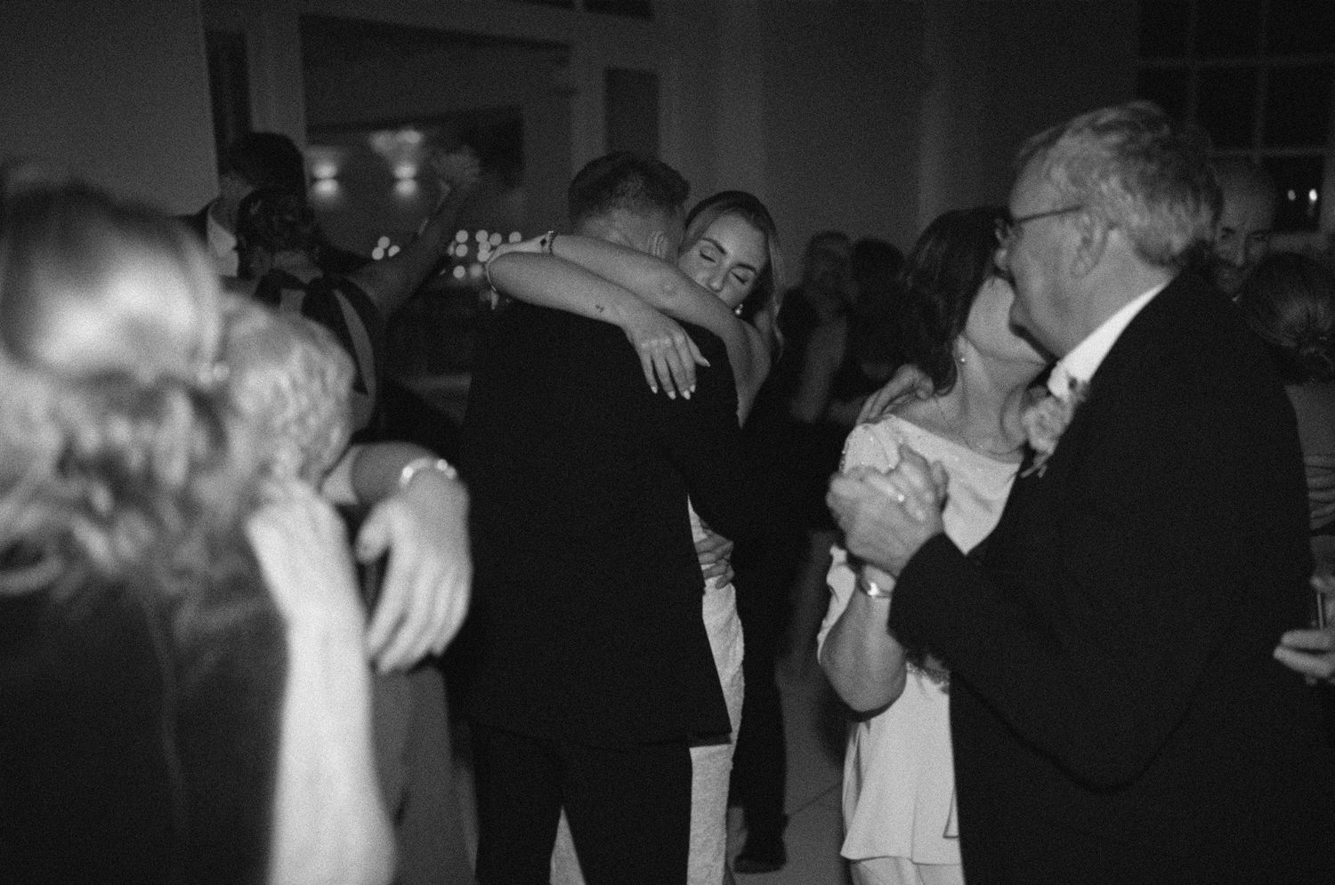 Couples slow dance together at an intimate black and white evening party or reception.