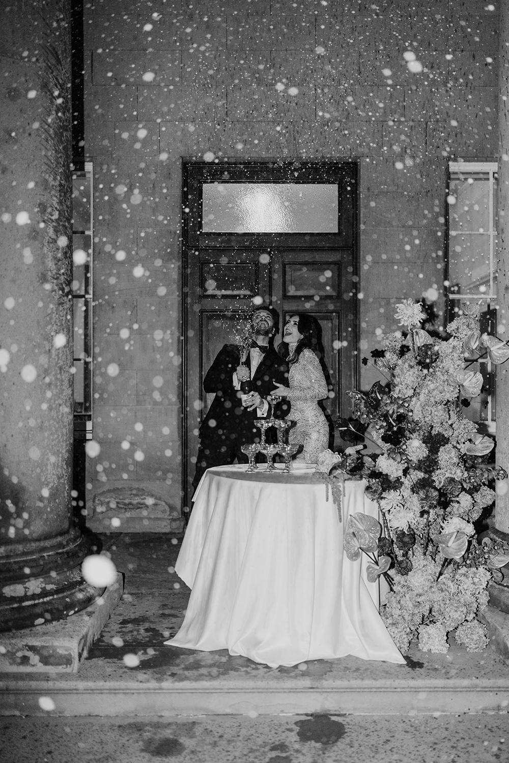 Bride and groom having a champagne spray while standing behind their champagne tower styled with autumnal flowers at Rise Hall.