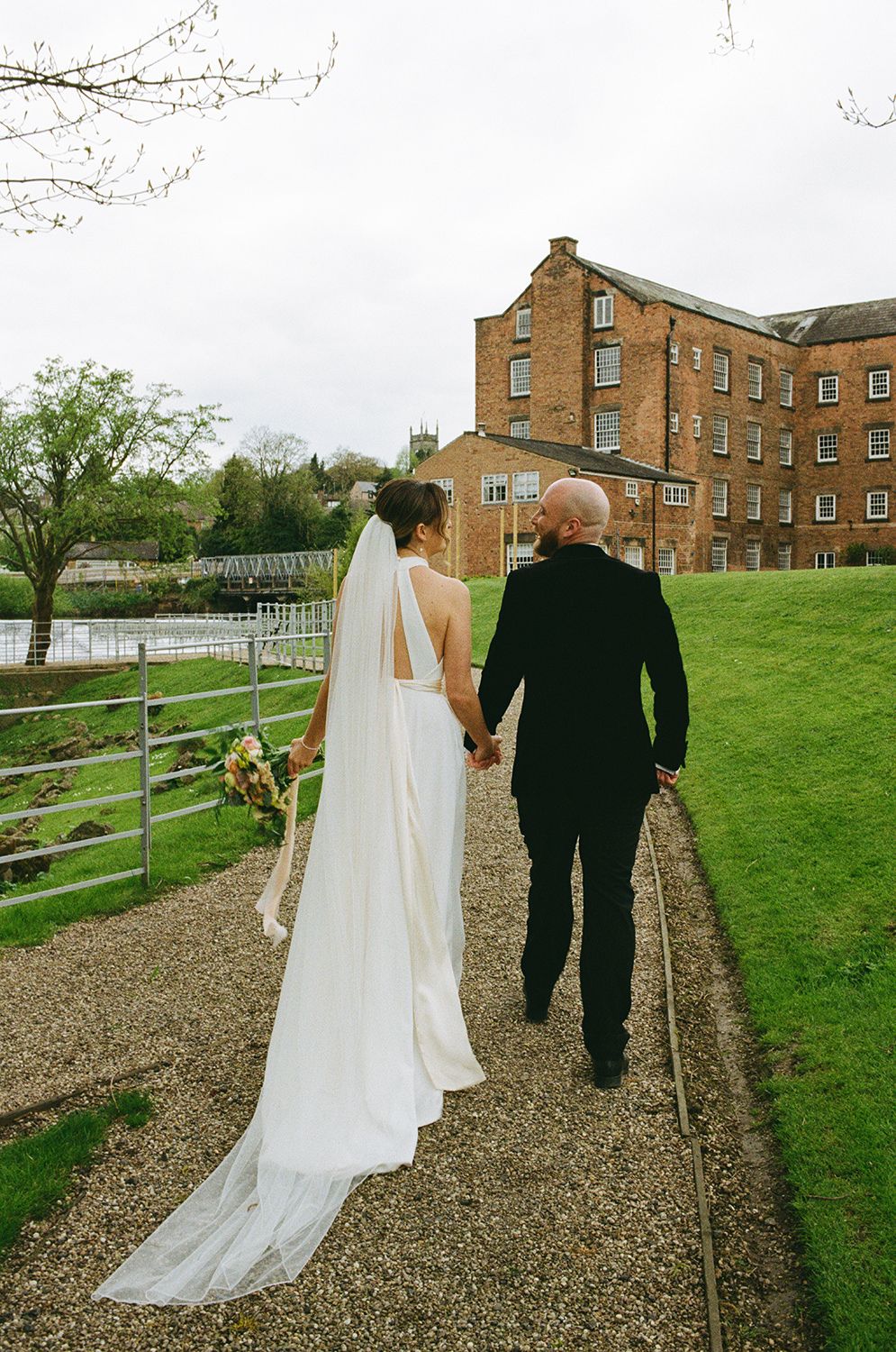 Bride and groom holding hands walking by the River Derwent.