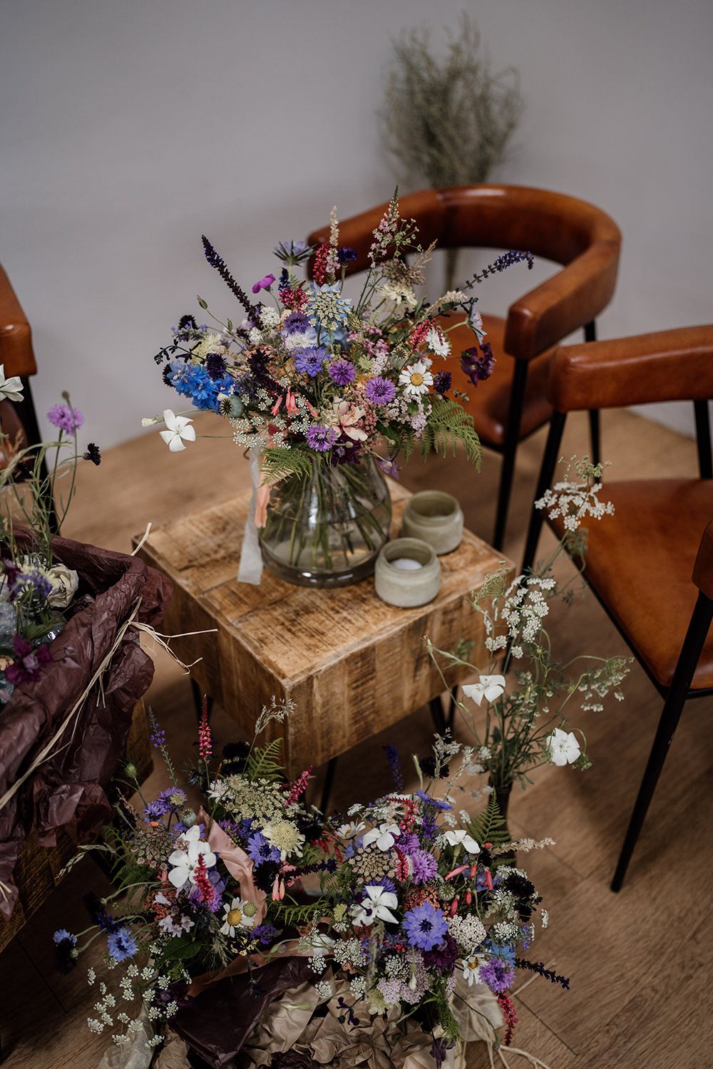 Bride and bridesmaids bouquets stood on a wooden table and leather chairs.
