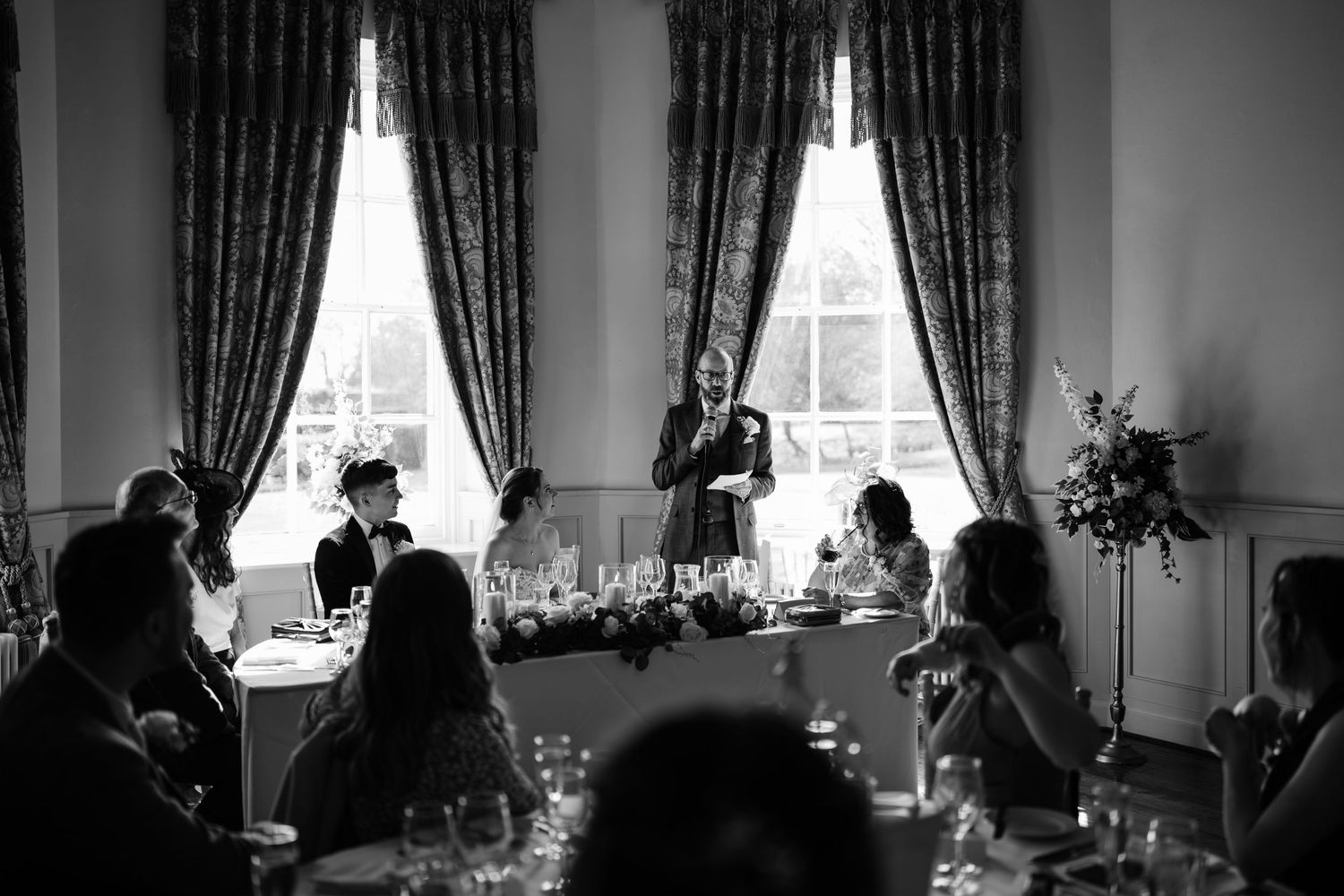 Father of bride does his wedding speech with close family sat around him.