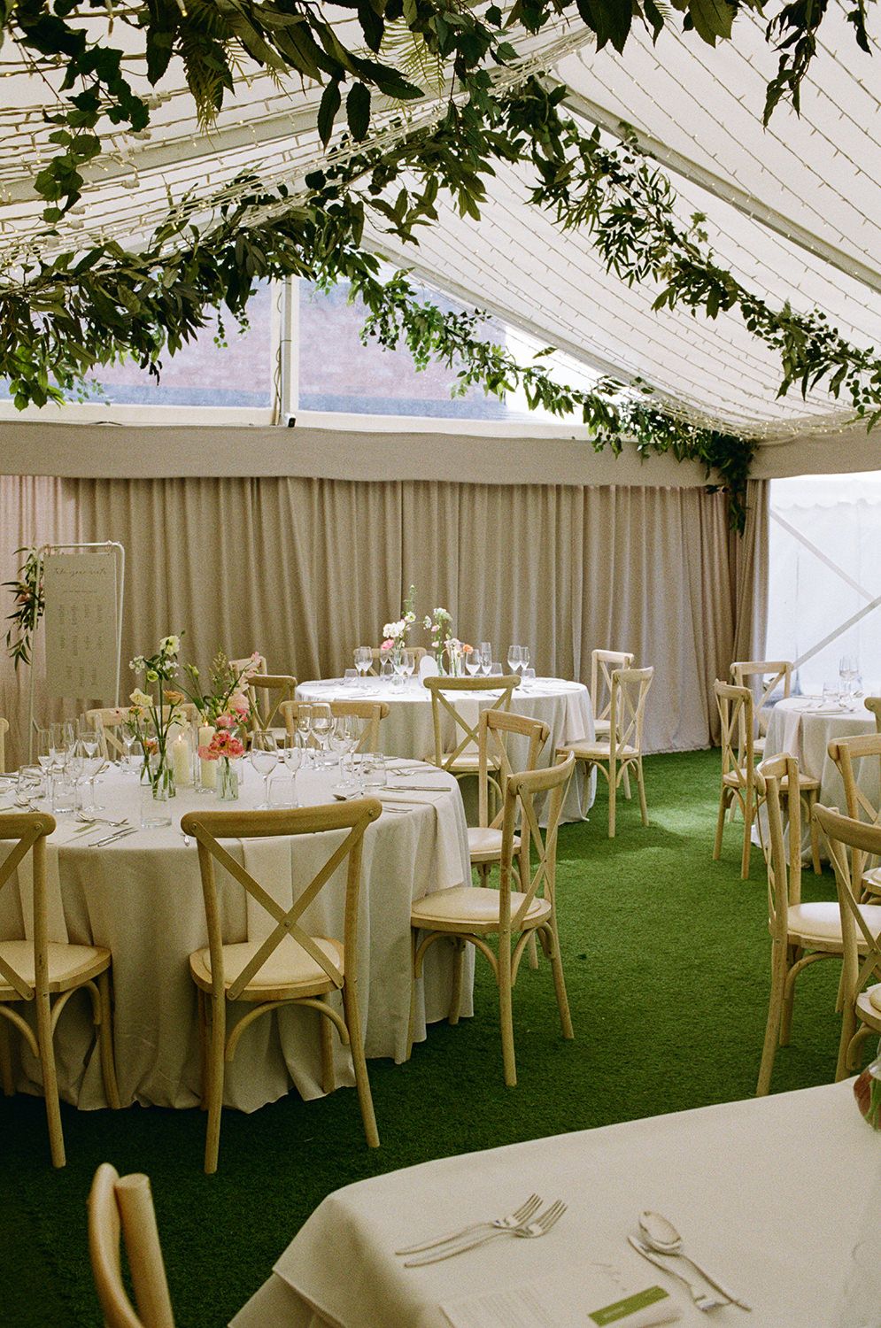 Wedding reception table styled with green fabric, candles, photographs and wine glasses.
