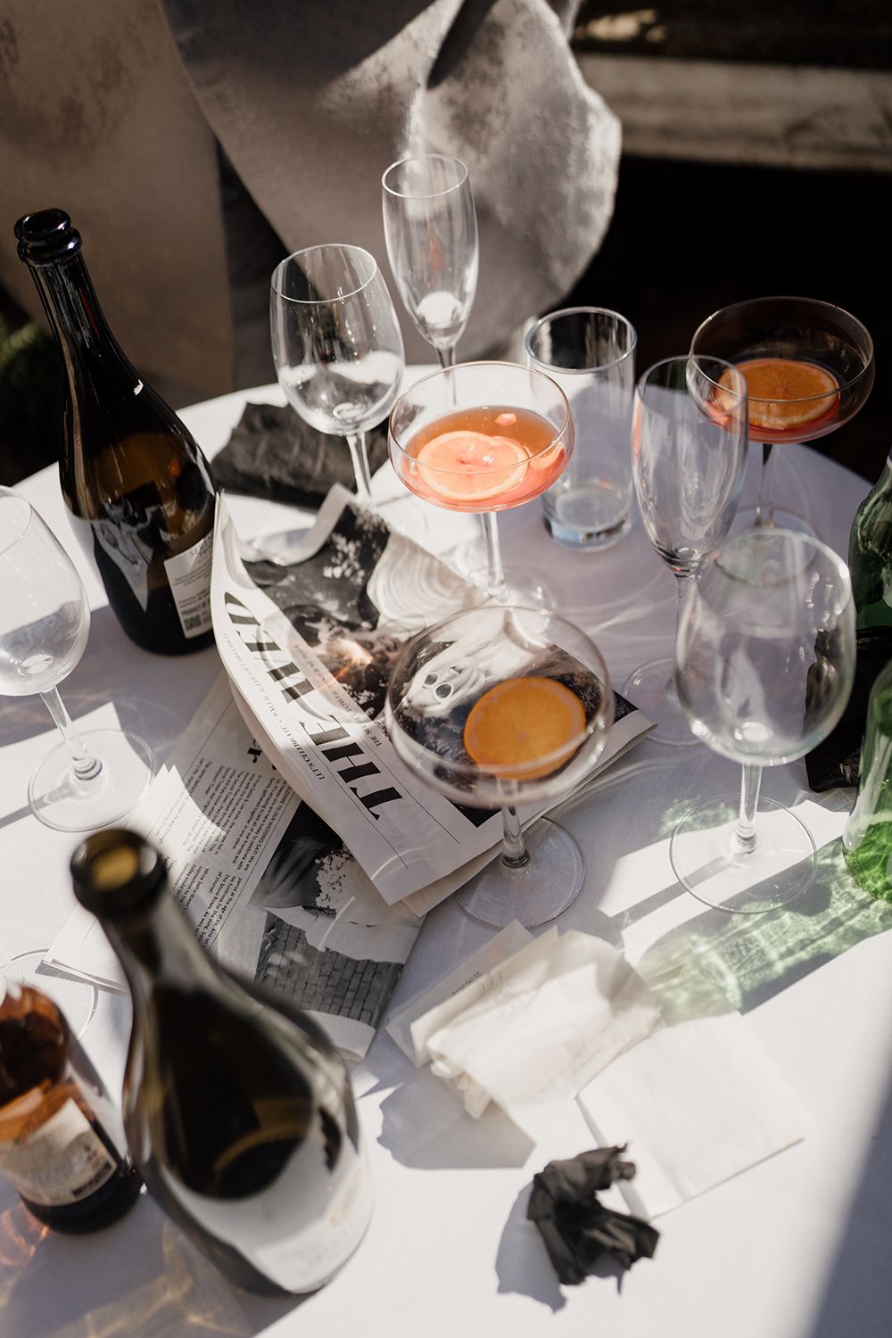 Candid editorial wedding photography details of empty glasses and vintage newspapers.